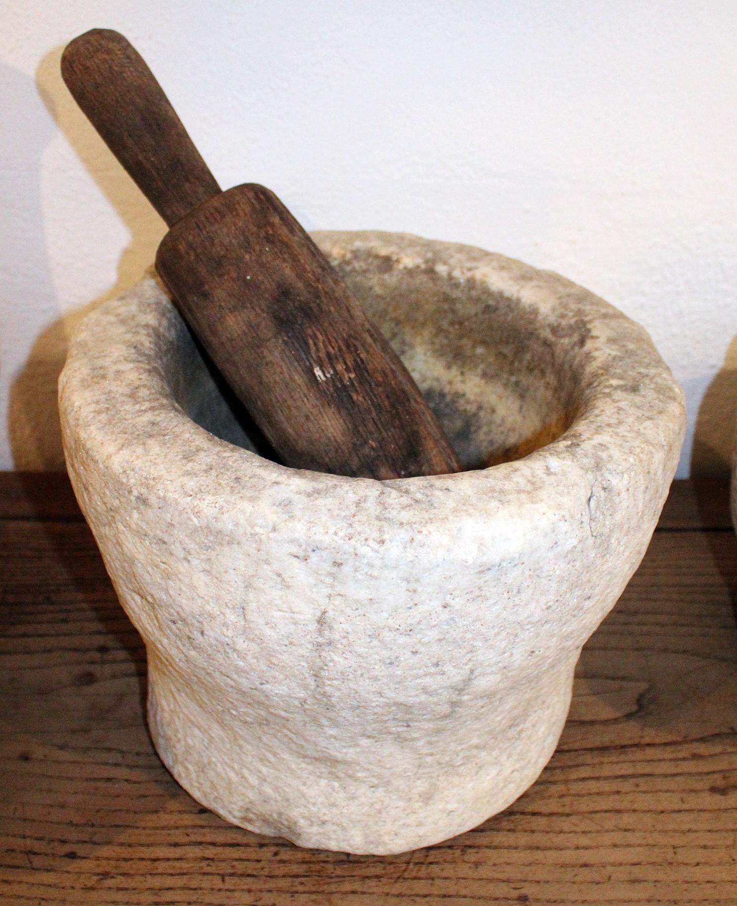 18th century Spanish hand carved stone kitchen mortar and wooden pestle, used in kitchens and pharmacies to prepare herbs for cooking or healing.

