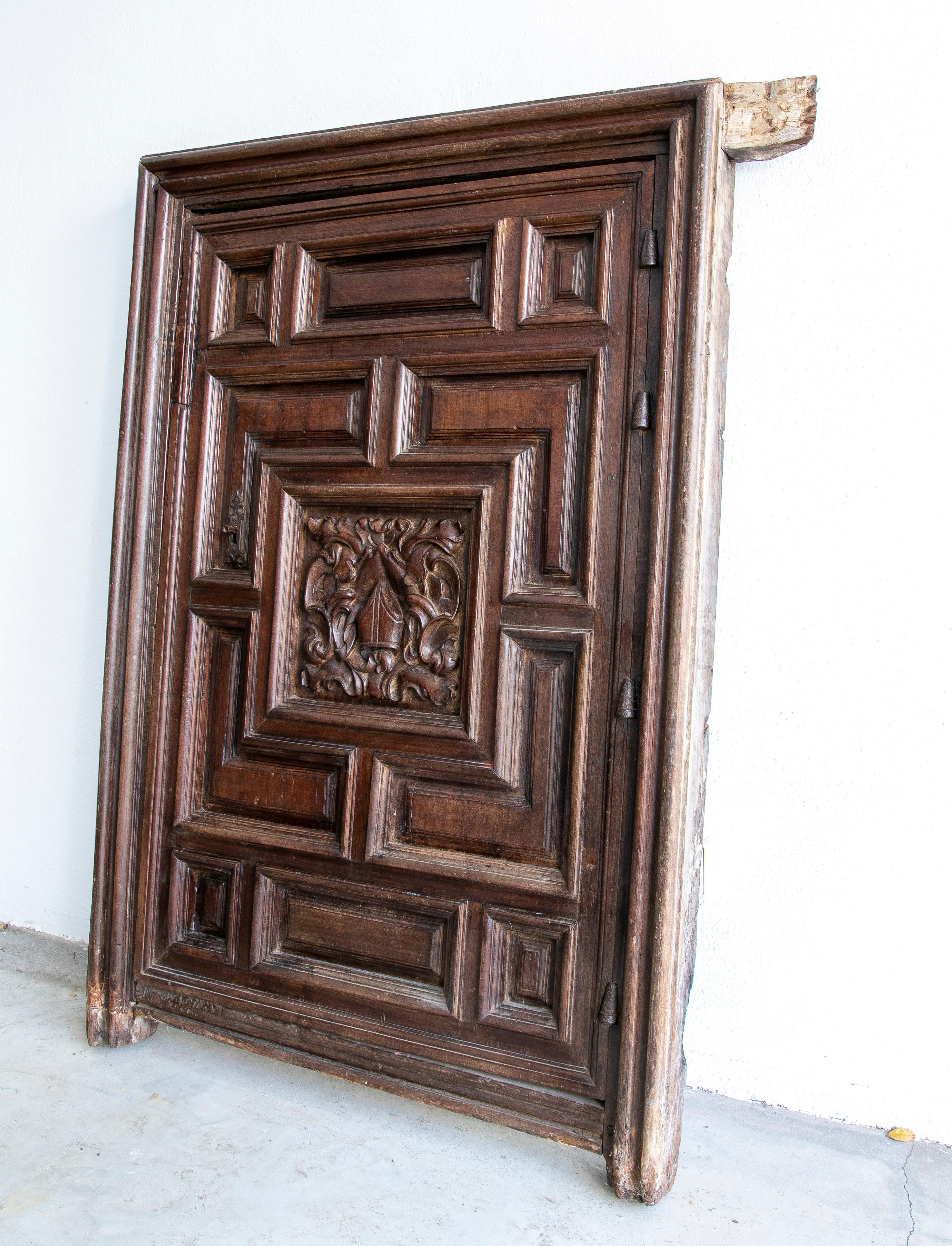 Antique 18th century Spanish hand carved walnut wide panel door with a central crest representing a mitre hat surrounded by acanthus leaf scrolls. The mitre is the traditional, ceremonial headdress of bishops and certain abbots in traditional