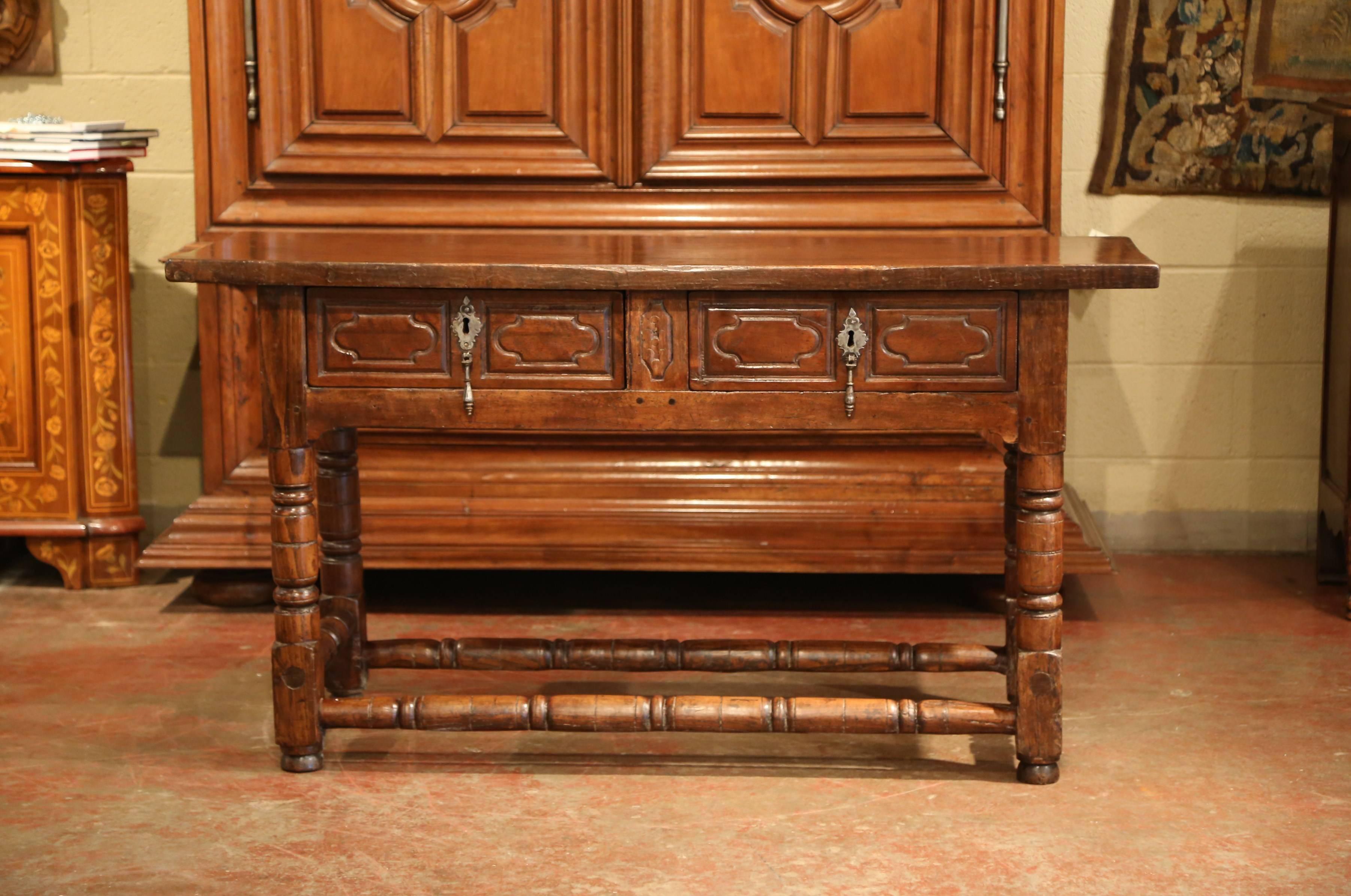 This elegant antique fruit wood console was crafted in Spain, circa 1780. The sofa table with four turned legs and matching stretcher at the base, features a pair carved drawers across the front embellished with original iron pull hardware. The top