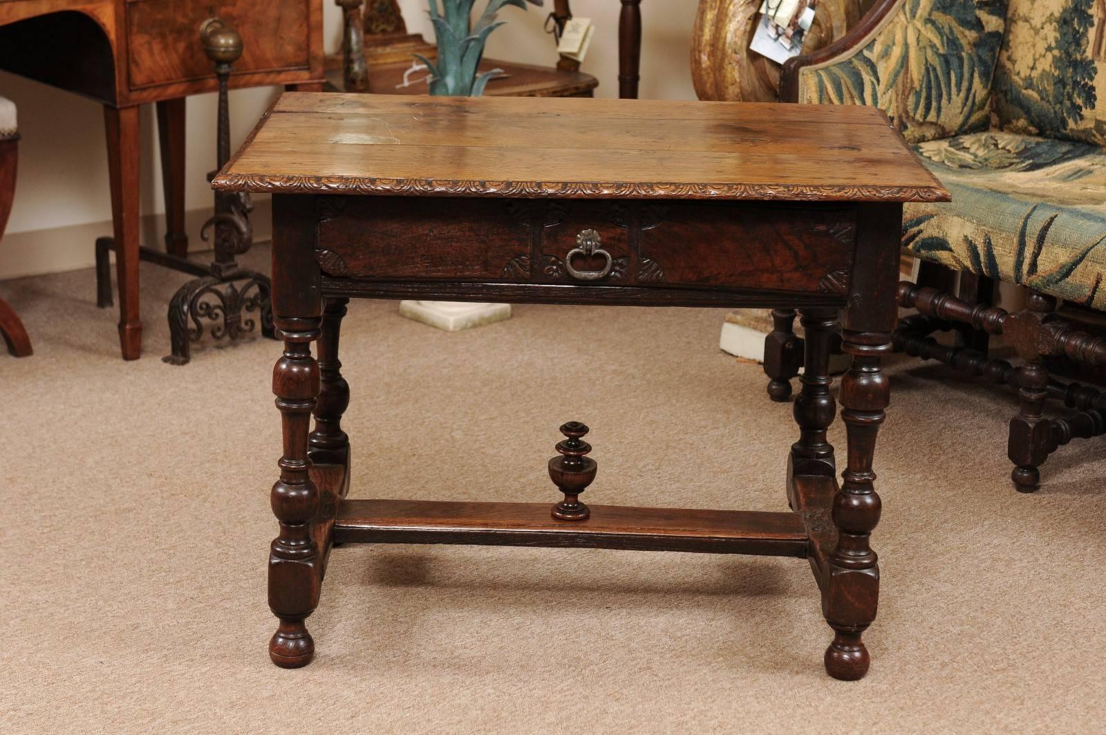 The Spanish 18th century oak table with rectangular top with carved boarder, drawer below with craved flowers and wrought iron pull. All resting on turned legs with stretcher and finial.