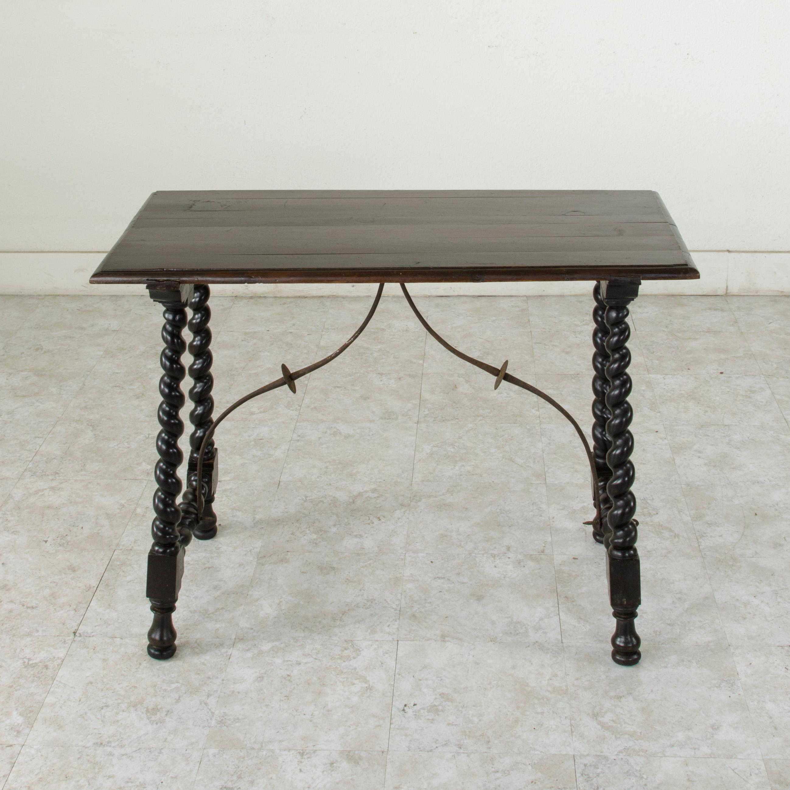 This mid-18th century Renaissance style walnut console table from Spain features hand-turned barley twist legs joined by an iron stretcher that provides additional stability. Its 19th century beveled top joins the hand pegged base by means of a
