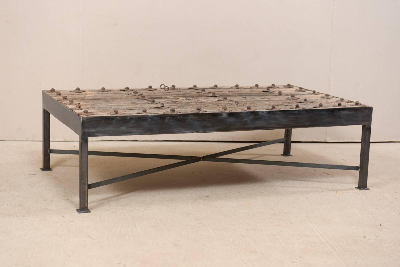 This is a custom coffee table made from an 18th century Spanish door. This wonderful coffee table has been fashioned from an 18th century Spanish door, with it's elongated wood planks, which are beautifully weathered with great patina, and adorn