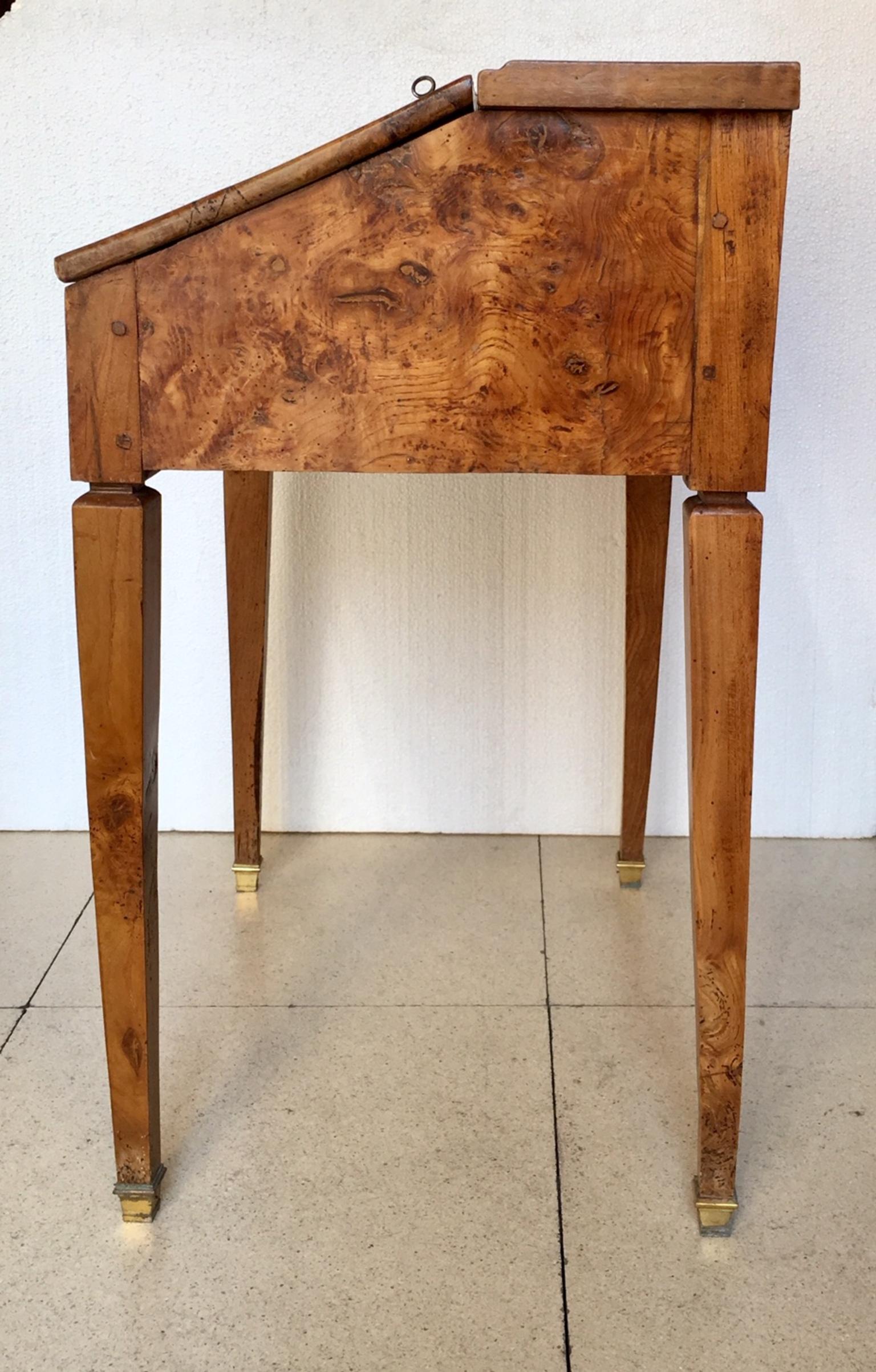 A small and elegant Spanish secretary desk, from the end of the 18th century, in olive wood, when you open the door a cover with original leather appears and some small internal drawers, the legs end in gilt bronze sabot.