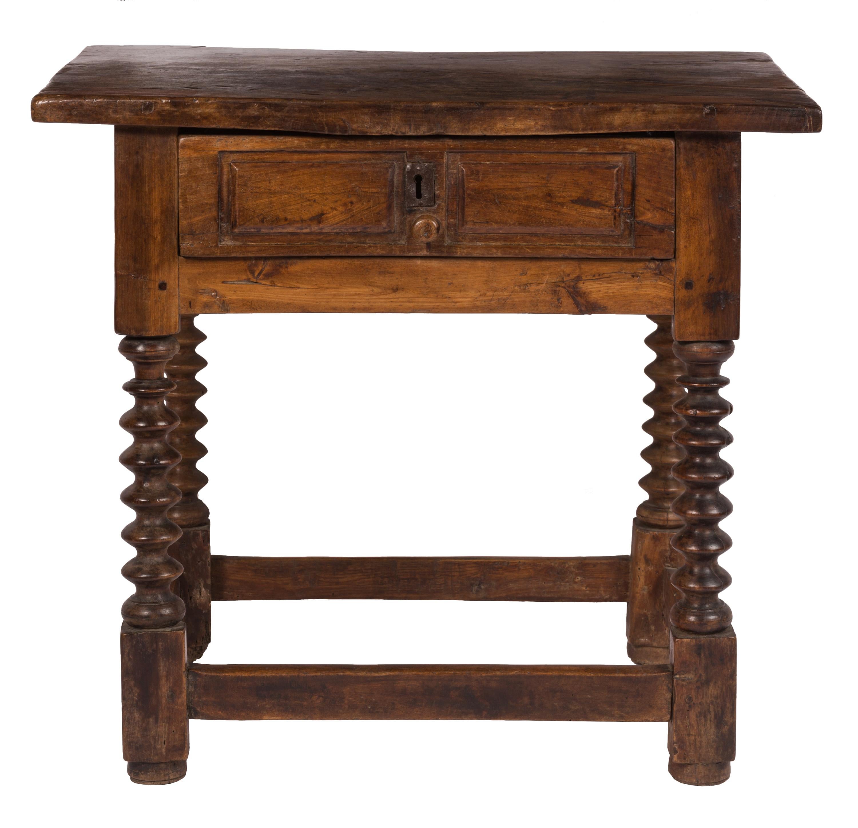 A small-sized 18th century Spanish shoemaker's table (mesa de zapatero) with a single drawer and spool turned legs. The tabletop is a single plank, legs attached with mortise and tenon joints - with the front two going all the way through the board.