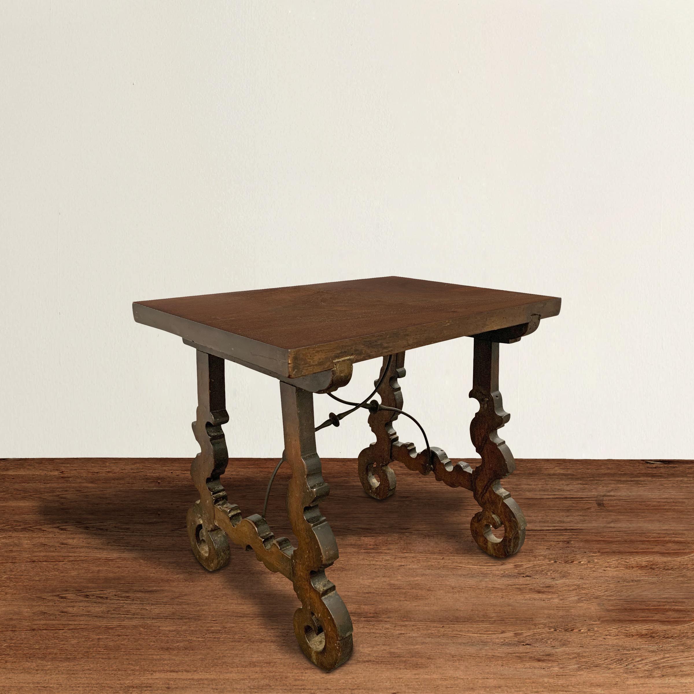 Ein wunderschöner, zierlicher spanischer Tisch aus dem 18. Jahrhundert, der aus Nussbaumholz gefertigt ist und hochgradig stilisierte, floral geschnitzte Beine hat, mit zwei handgeschmiedeten Eisenträgern, die die Basis stützen. Die Platte wurde neu