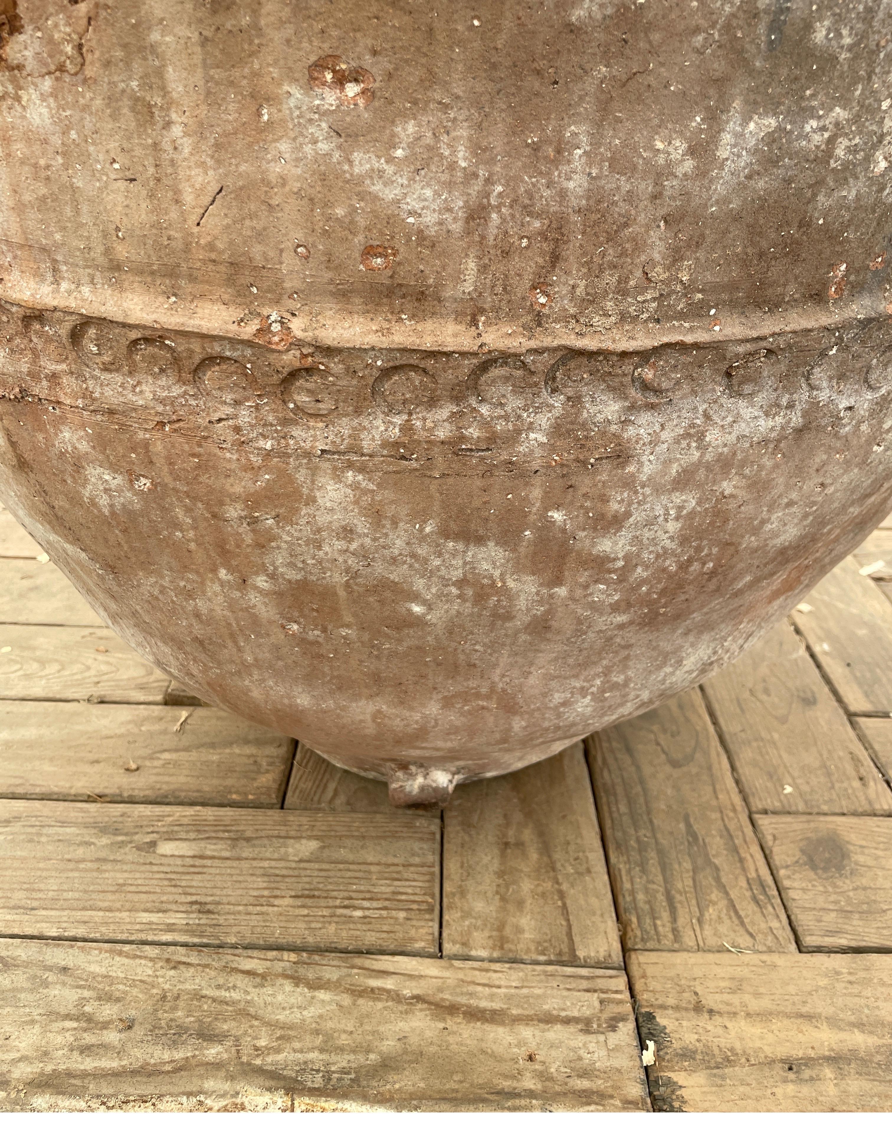 This large olive jar from Spain is great on either side of a front door or inside as a sculpture. The terra-cotta color with black detail covered in white plastering give ayers of a beautiful patina. Measures: 27 diameter x 35 tall opening at top