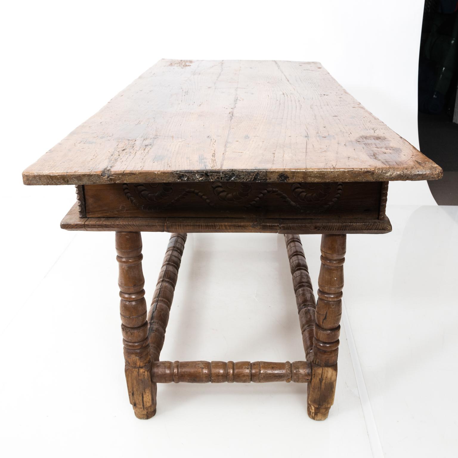 Spanish two-drawer walnut table with metal escutcheons and hand carved detail throughout. The table also features ring turned legs and box stretcher. This piece weighs more than 70 LBS.
 