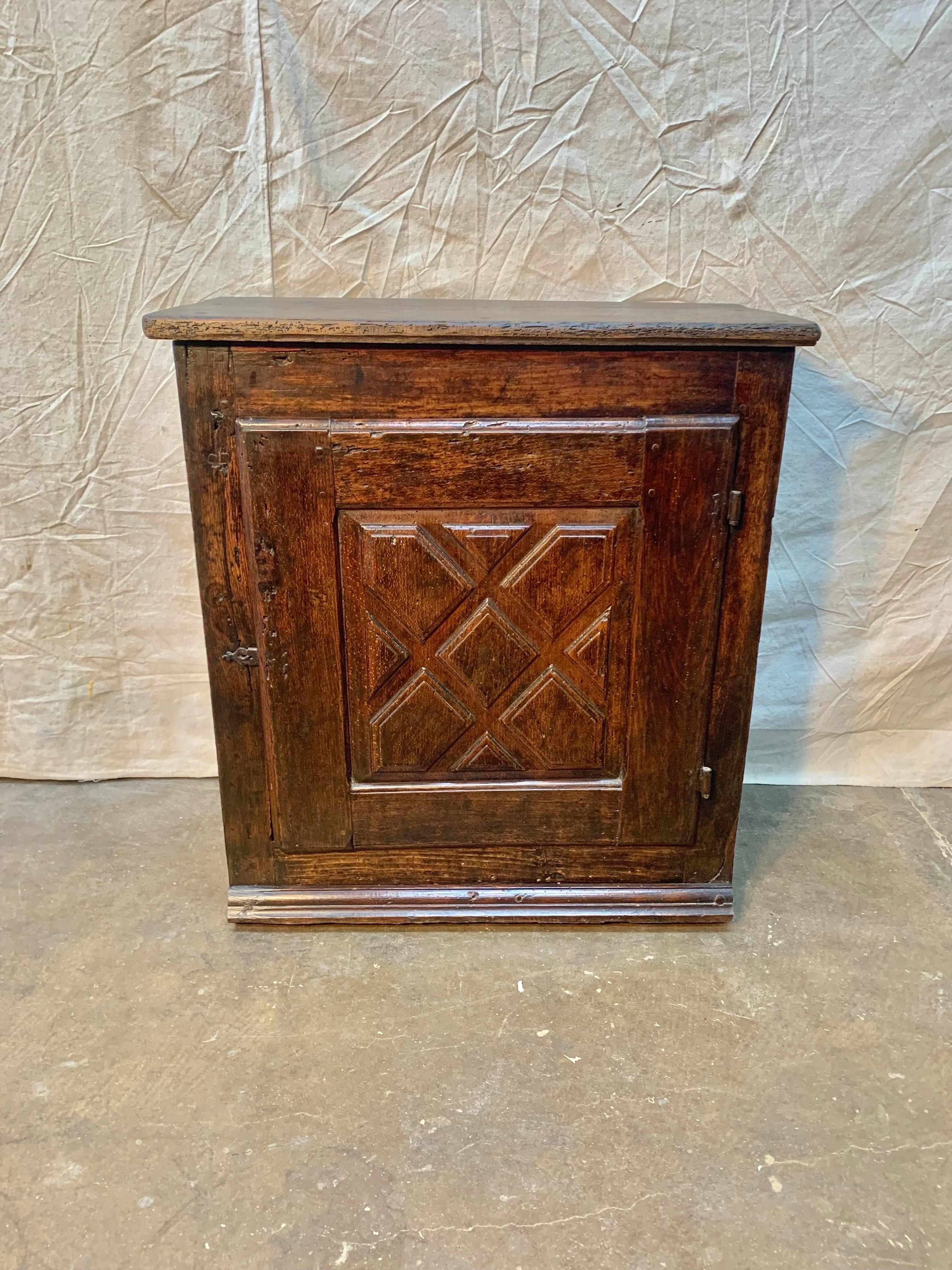 This beautiful primitive 18th century Spanish Walnut Cabinet features one door that has been hand carved in a geometric pattern and opens to reveal one shelf which is typical for this type of Spanish furniture. The piece retains its original hand