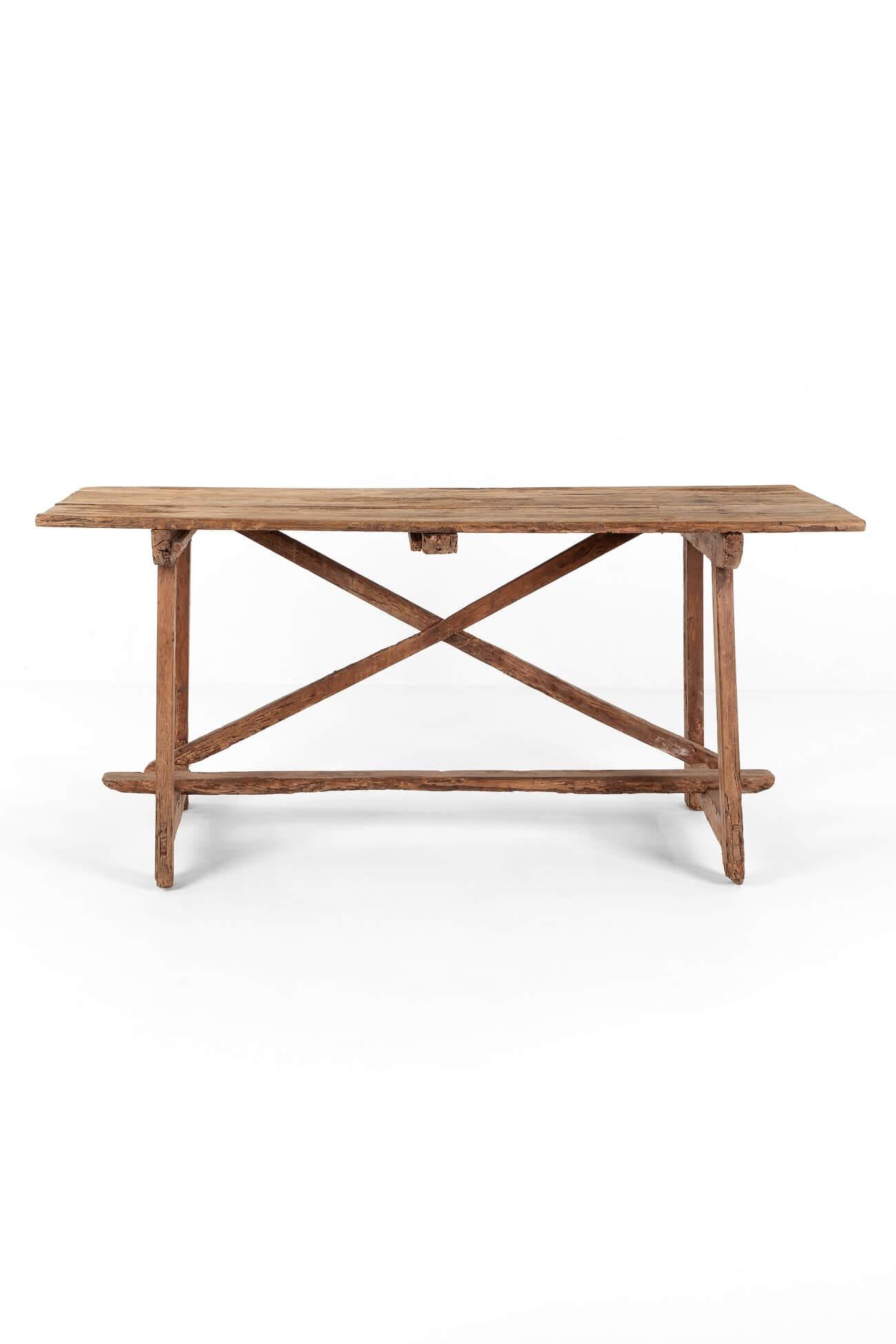 A superb 18th-century rustic walnut table from Catalonia.

The generous weathered three-plank top is supported by an X-frame support to one side of the table and a central stretcher that overrides at each end. The top is supported by two trestle end