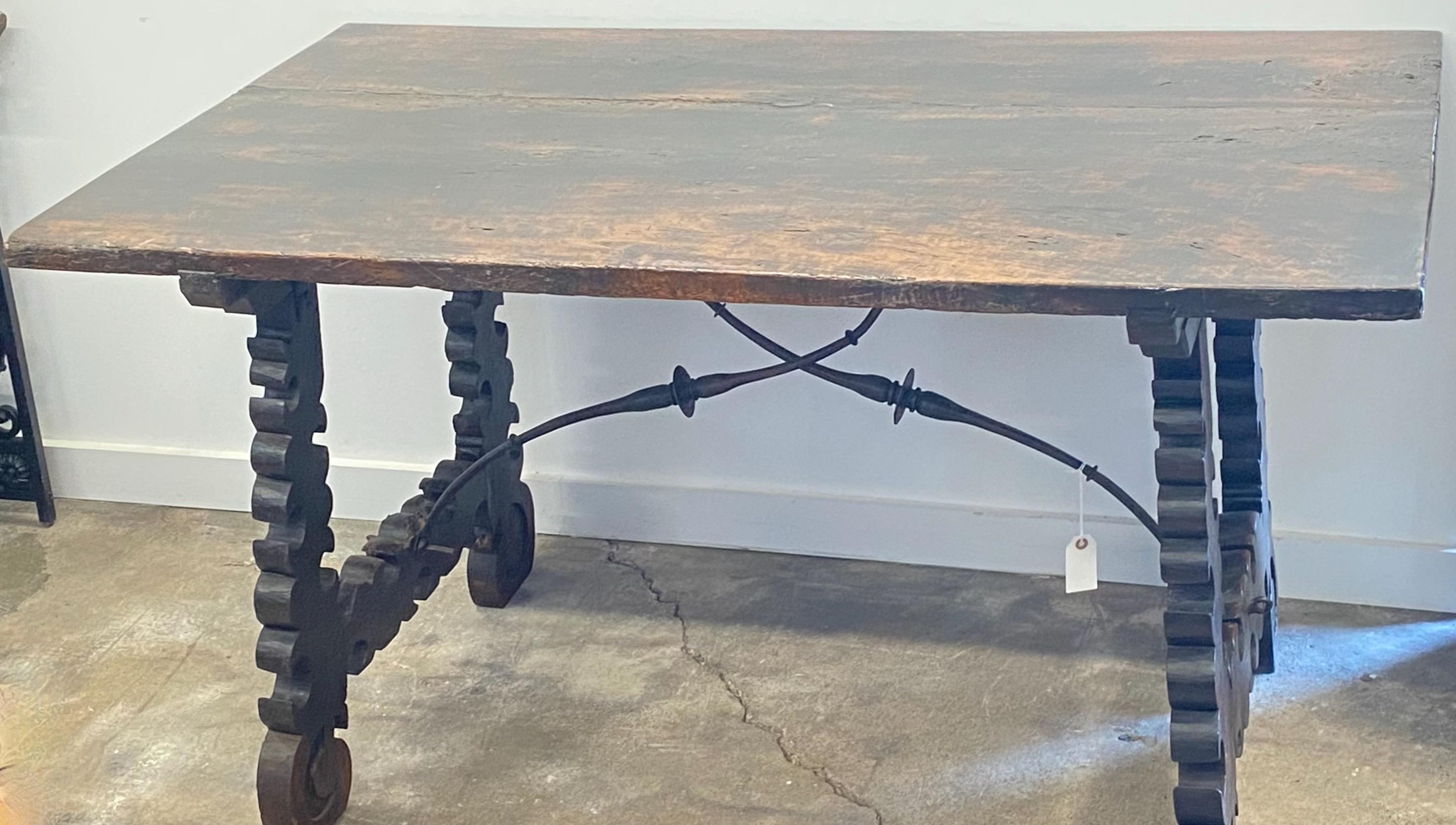 An 18th century walnut table. Soundly constructed from walnut, with original hand forged wrought iron braces and classical lyre shaped legs. 
Wonderfully worn and aged patina, some old patches and repairs and having signs of use that you would