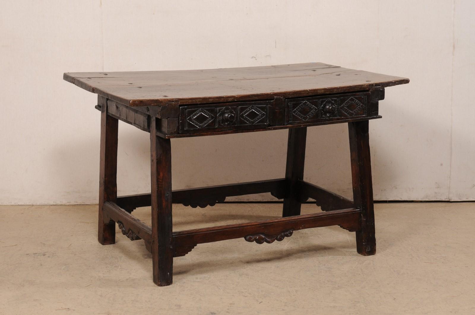 A Spanish carved-walnut occasional table with drawers from the 18th century. This antique table from Spain, created from rich walnut wood, has a rectangular-shaped top, which overhangs the apron below which houses a pair of half drawers at one long