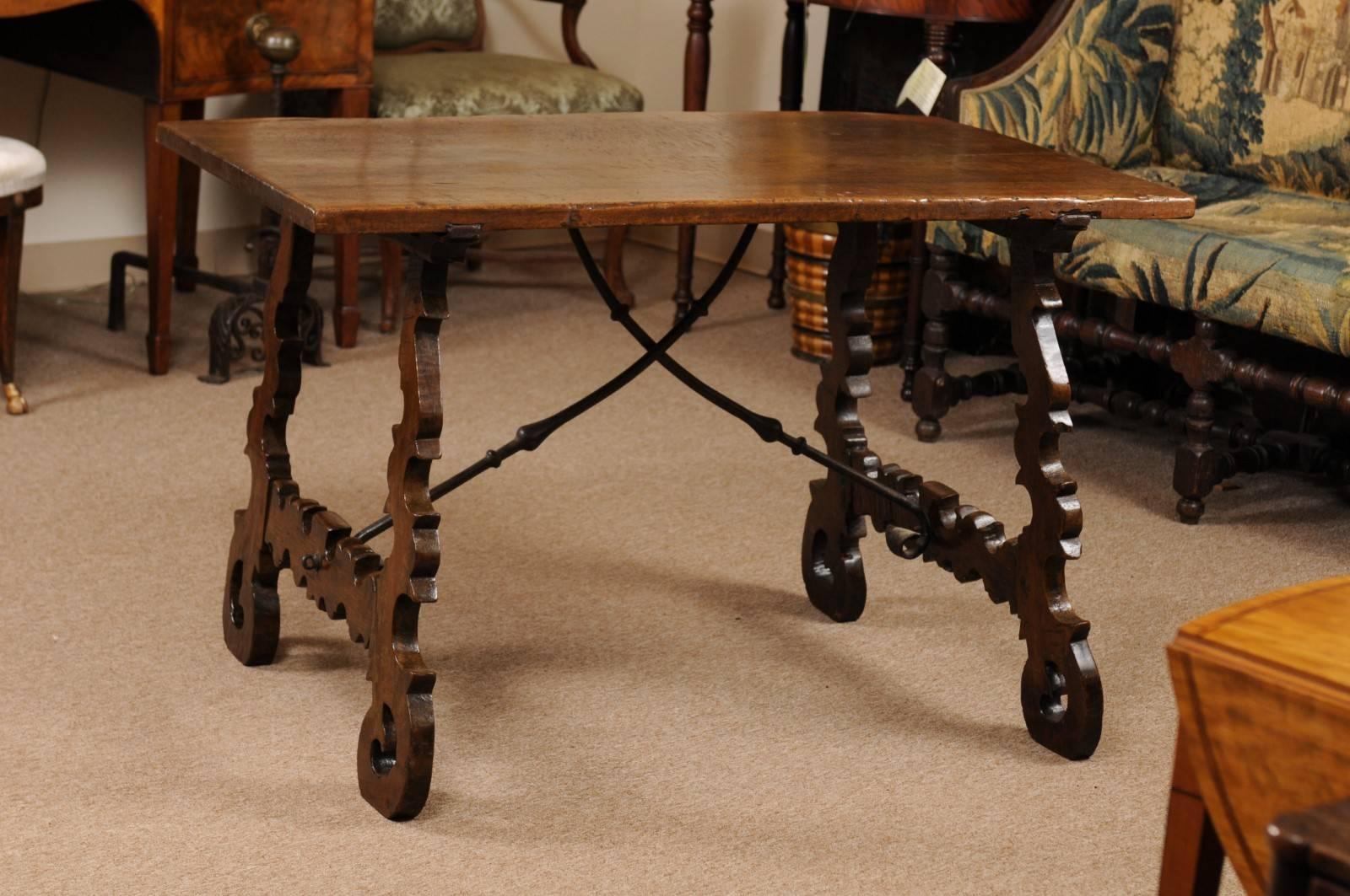 The 18th century Spanish table in walnut with carved pierced lyre shaped legs and wrought iron stretcher.