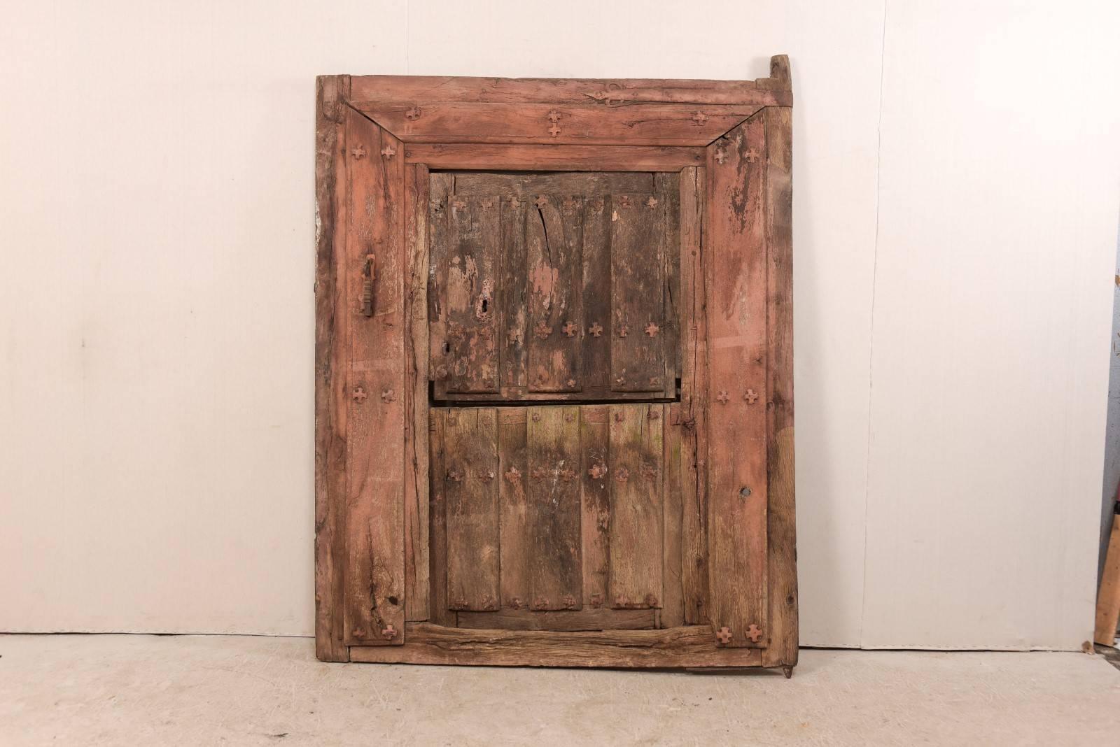 A Spanish 18th century split-door within it's original casing. This antique architectural piece from Spain features a shorter, half door (similar to a Dutch style door, split horizontally at it's center) set within the original casing. This piece
