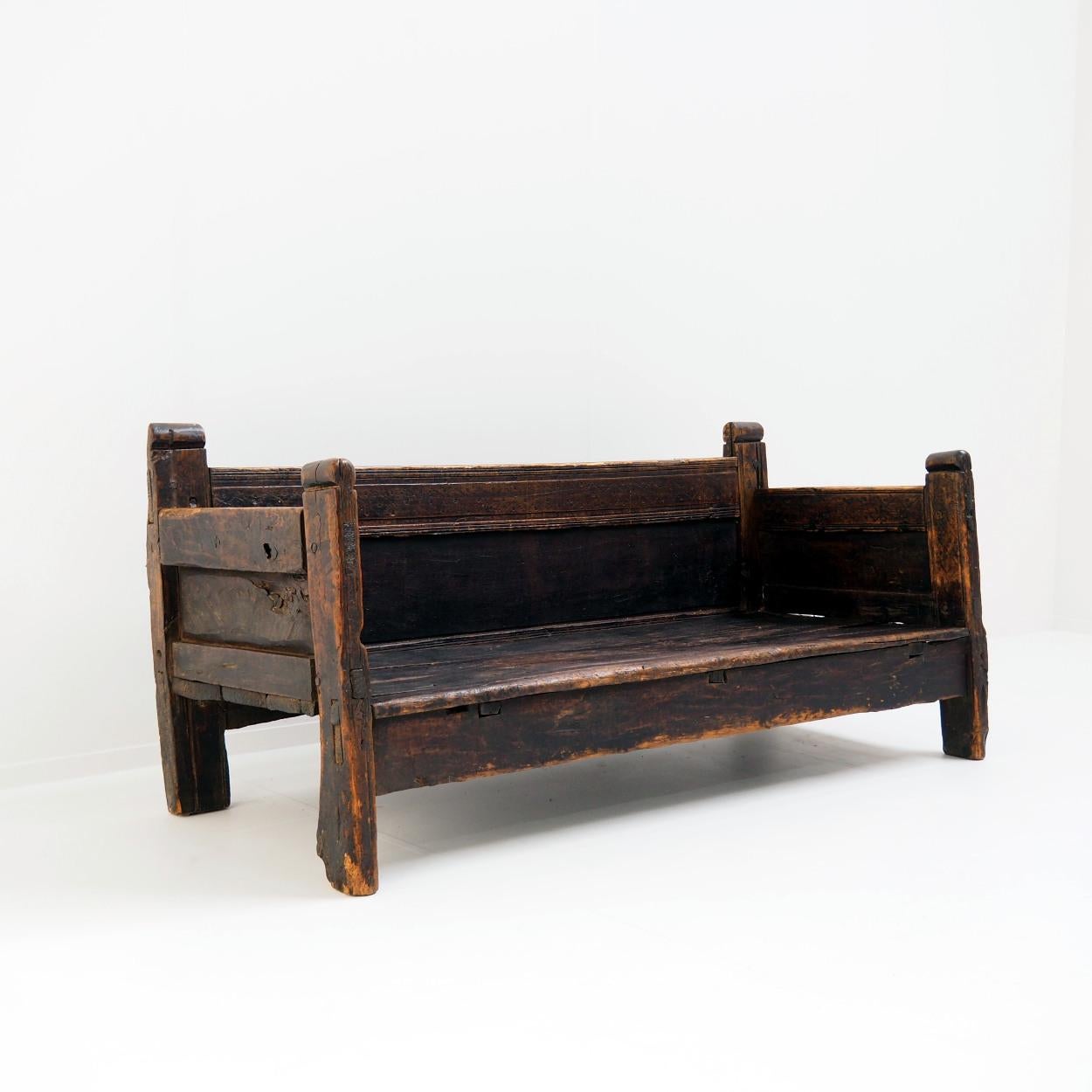 Beautiful 18th century wooden bench with many signs of wear, and decorated with primitive and rural wood carvings. The colour is a very dark brown (stained) that has acquired a beautiful patina.

Please note that the seat is quite low and deep and