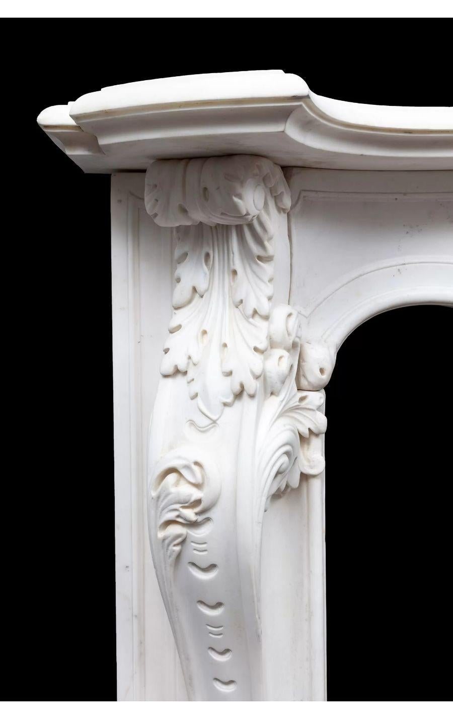 A large antique English Rococo Statuary marble chimneypiece from the George II period.

The serpentine shaped panelled frieze, beneath a moulded serpentine shelf is centred by a richly carved cartouche with C scrolls and female head. The tall,