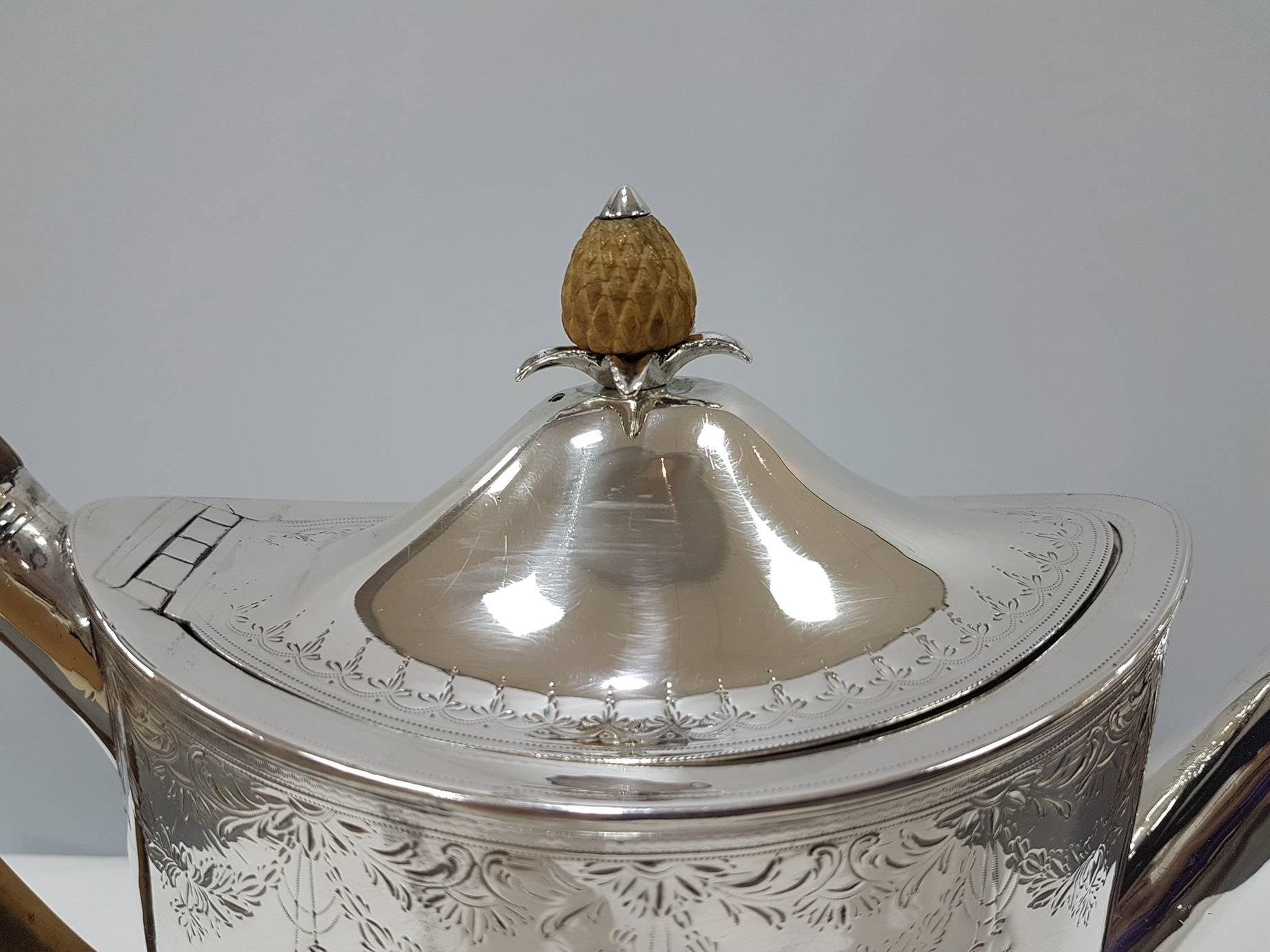 Antique Georgian sterling silver teapot on Stand, having a hand-engraved oval body, a hinged domed lid with wooden finial, a wooden scroll handle, and sitting on its original stand with four flanged feet. Made by Peter and Ann Bateman of London in