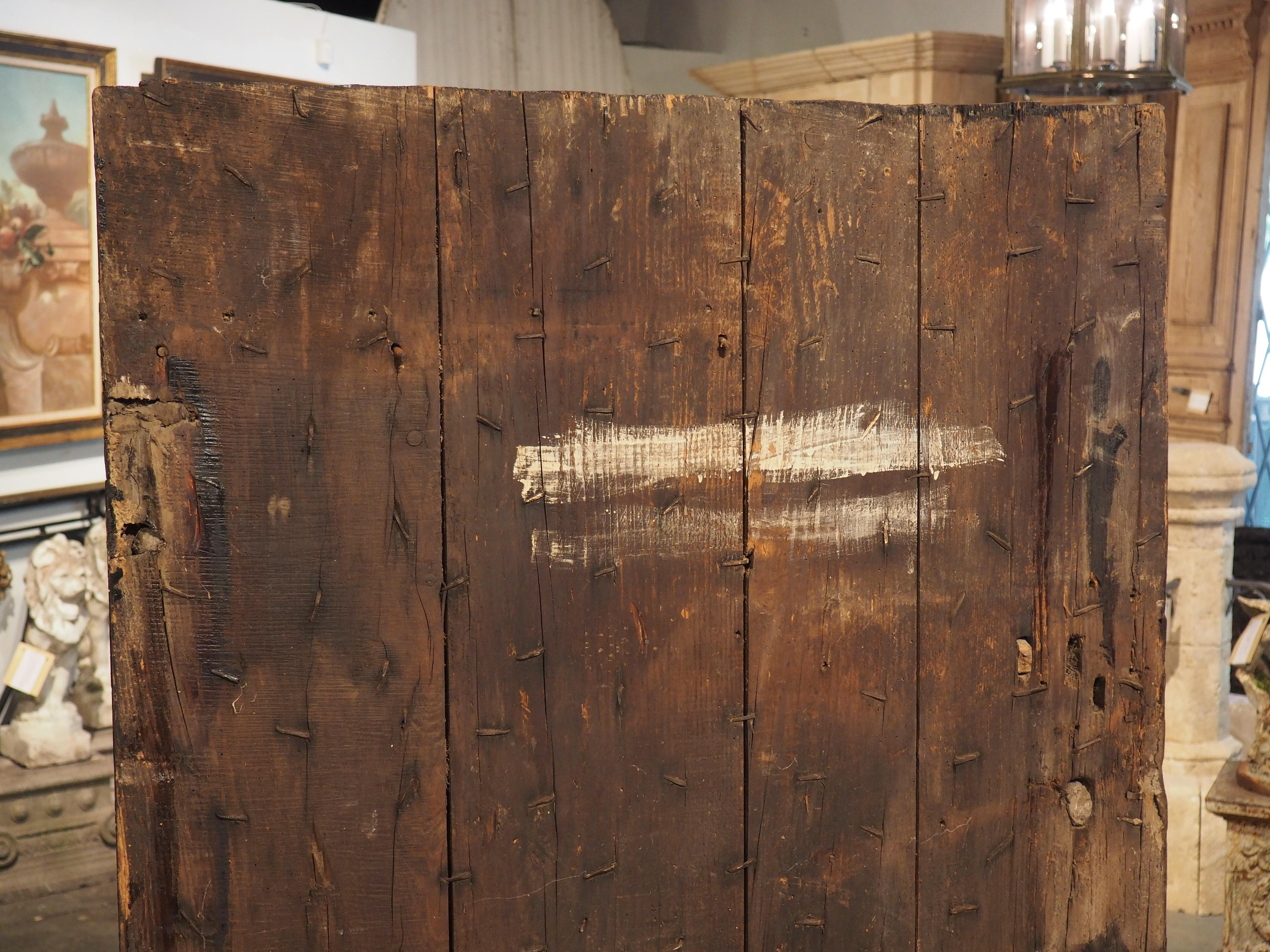 Possibly inspired by earlier Spanish doors, this studded farm door was hand-carved in France in the 1700’s. The 64 ½ inch tall door has iron nailheads of various sizes hammered into the front of the door, arranged in linear rows. Spanish furniture