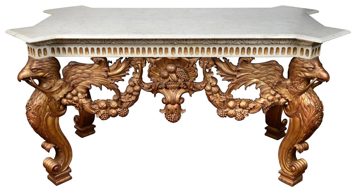 A very impressive and imposing 18th Century style marble topped, carved gilt wood console table. This table has its original Carrera marble top with canted corners. Four wonderful hand carved winged Griffin supports to the corners, swags of