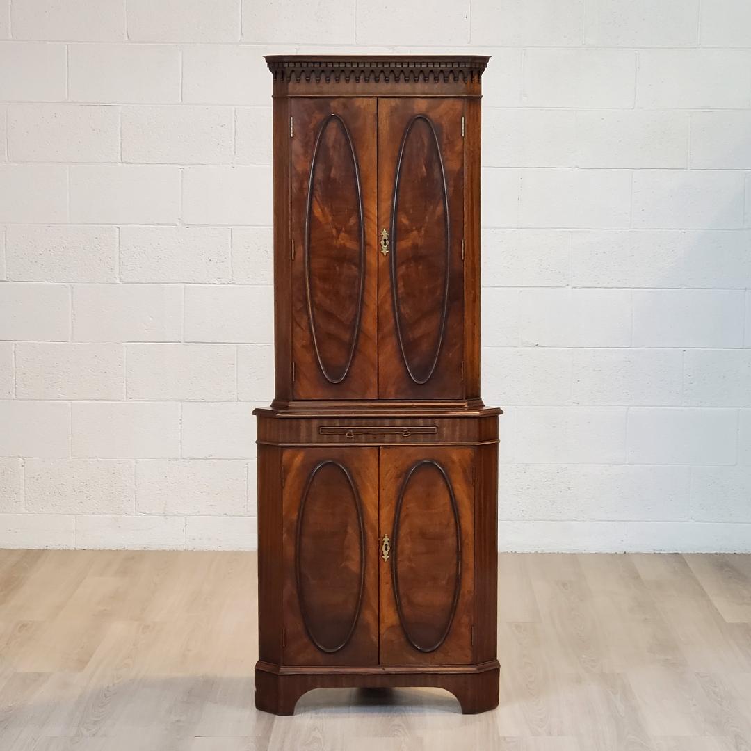 Here we have a lovely 18th century style corner cabinet, English, mahogany with full wood doors with oval framed crotch or feathered mahogany centre panels. A good look for that English cottage appeal. 
Behind the upper doors are shelves with