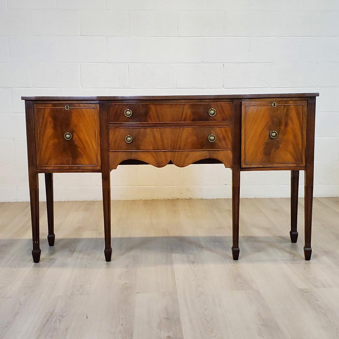 An elegant 18th century style, English, Mahogany Sideboard, in the classic Georgian Style. The top has a ribbon cut veneer pattern and the face of the cabinet has a crotch or flame mahogany pattern in keeping with the time honored craftsmen of 200