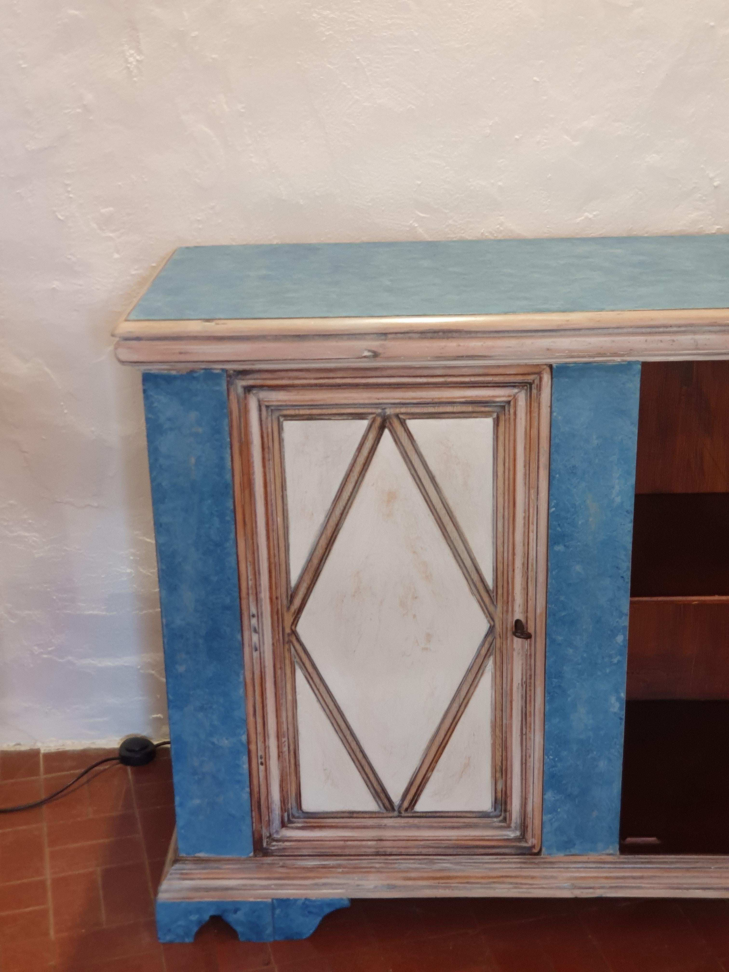 An elegant vintage Italian hand-painted wooden buffet cabinet , in pale blue, beige and cream colors. This Italian console cabinet is fitted with two doors. Each door has a stylized diamond carving typical of 18th century Italian beliefs . The doors