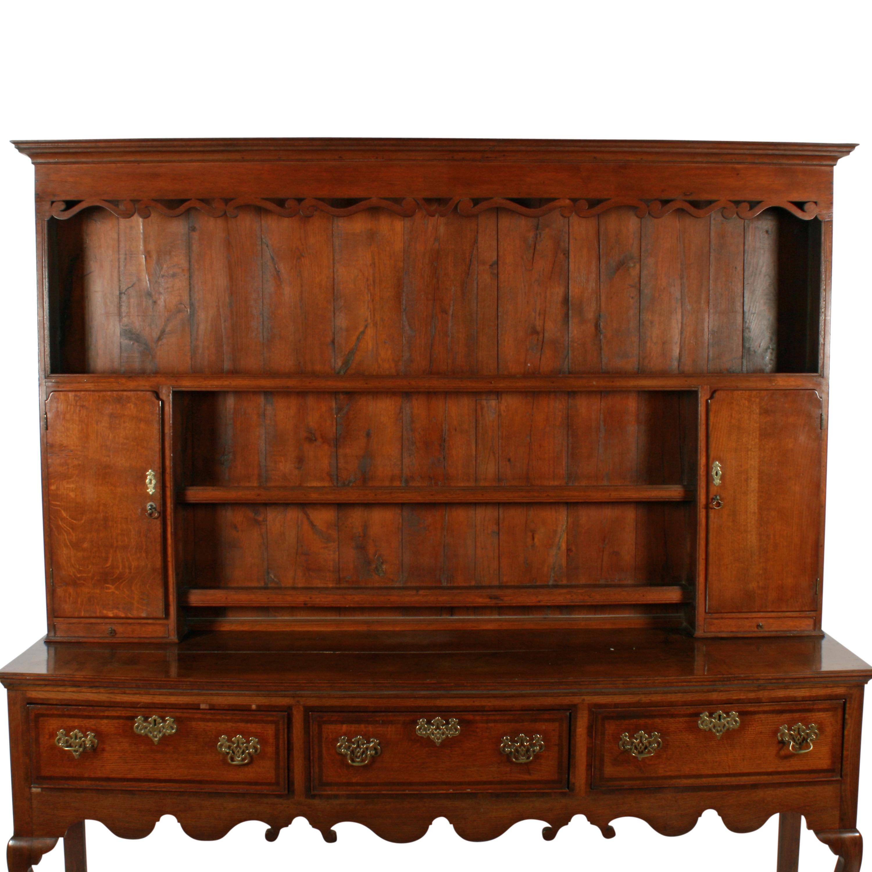 18th century style oak dresser

A George II style oak three-drawer dresser and delft rack.

The dresser base has cabriole shaped front legs with a 'Knight's Foot' shaped toe and square back legs.

The three drawers are crossbanded with