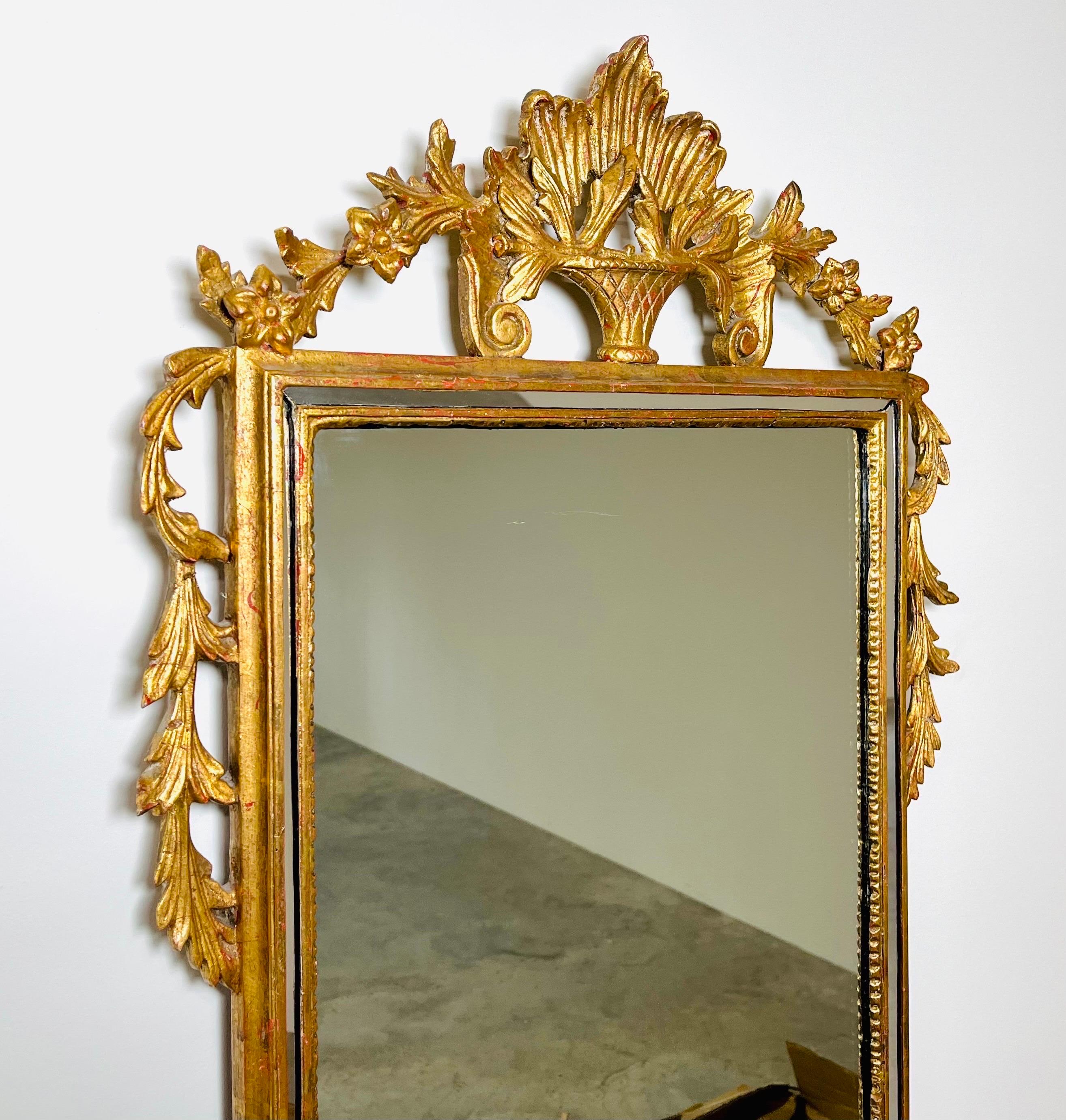 18th century Style wall mirror carvers guild adam with urn and weathered pendants.
 Hand carved details in gilt gold with mirrored border that ads beautiful depth. In great condition. 
This mirror originally hung in the lobby of the prestigious