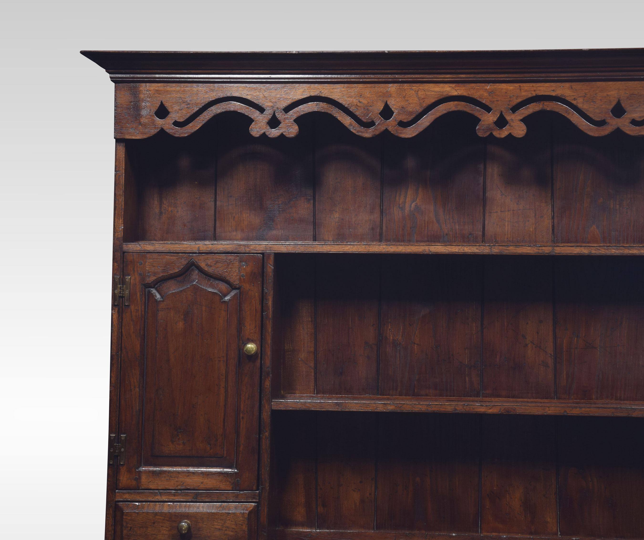 18th-century style oak dresser, having a deep boarded rack with canopy frieze above an arrangement of shelves and cupboard ends with drawers below. The base section having three fielded drawers above three conforming arched panelled cupboard doors