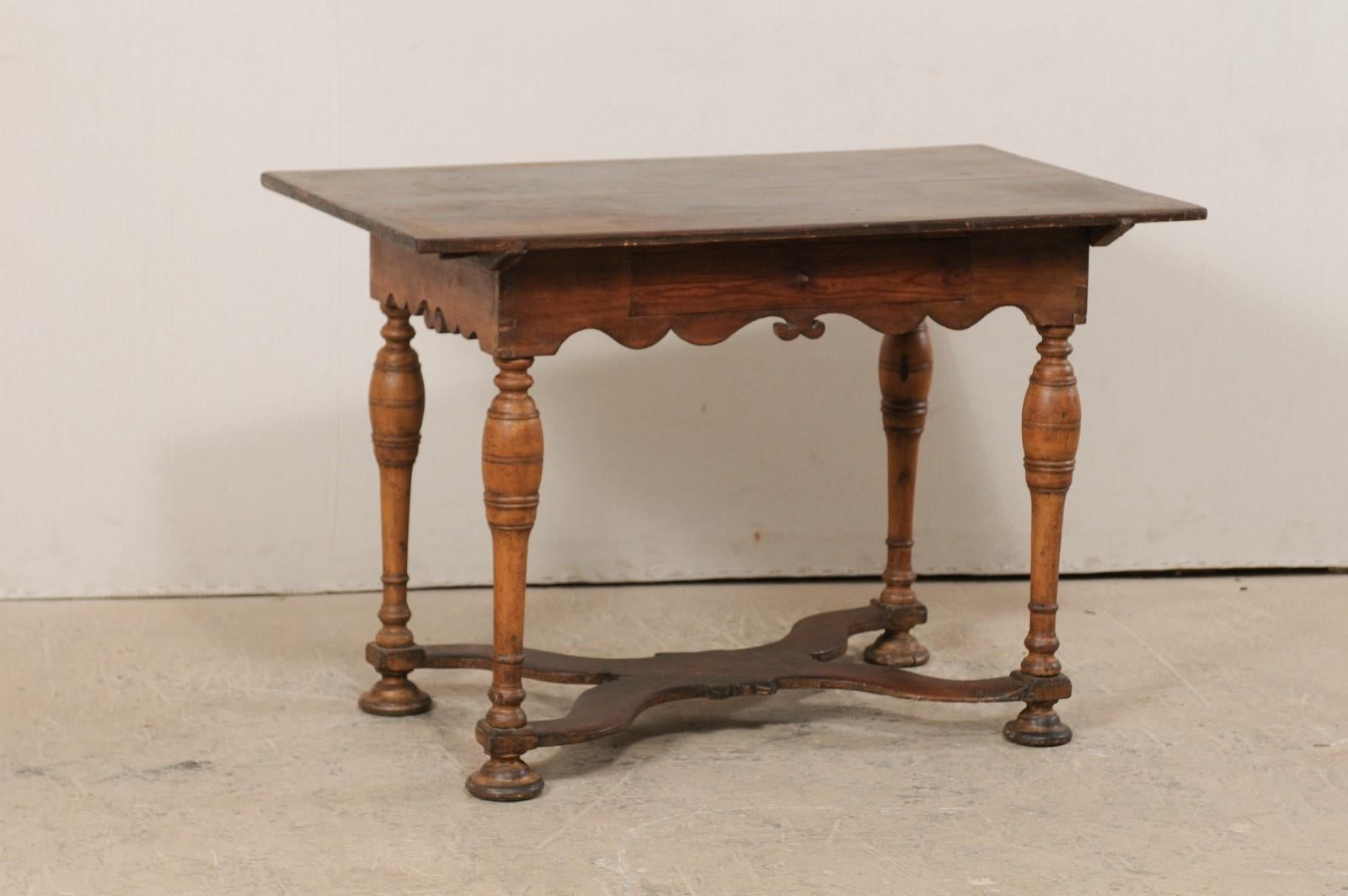 A Swedish Baroque carved wood table from the 18th century. This antique occasional table from Sweden features a rectangular-shaped overhanging top, with rests above a beautifully scalloped skirt, carved along all sides. The table is presented upon