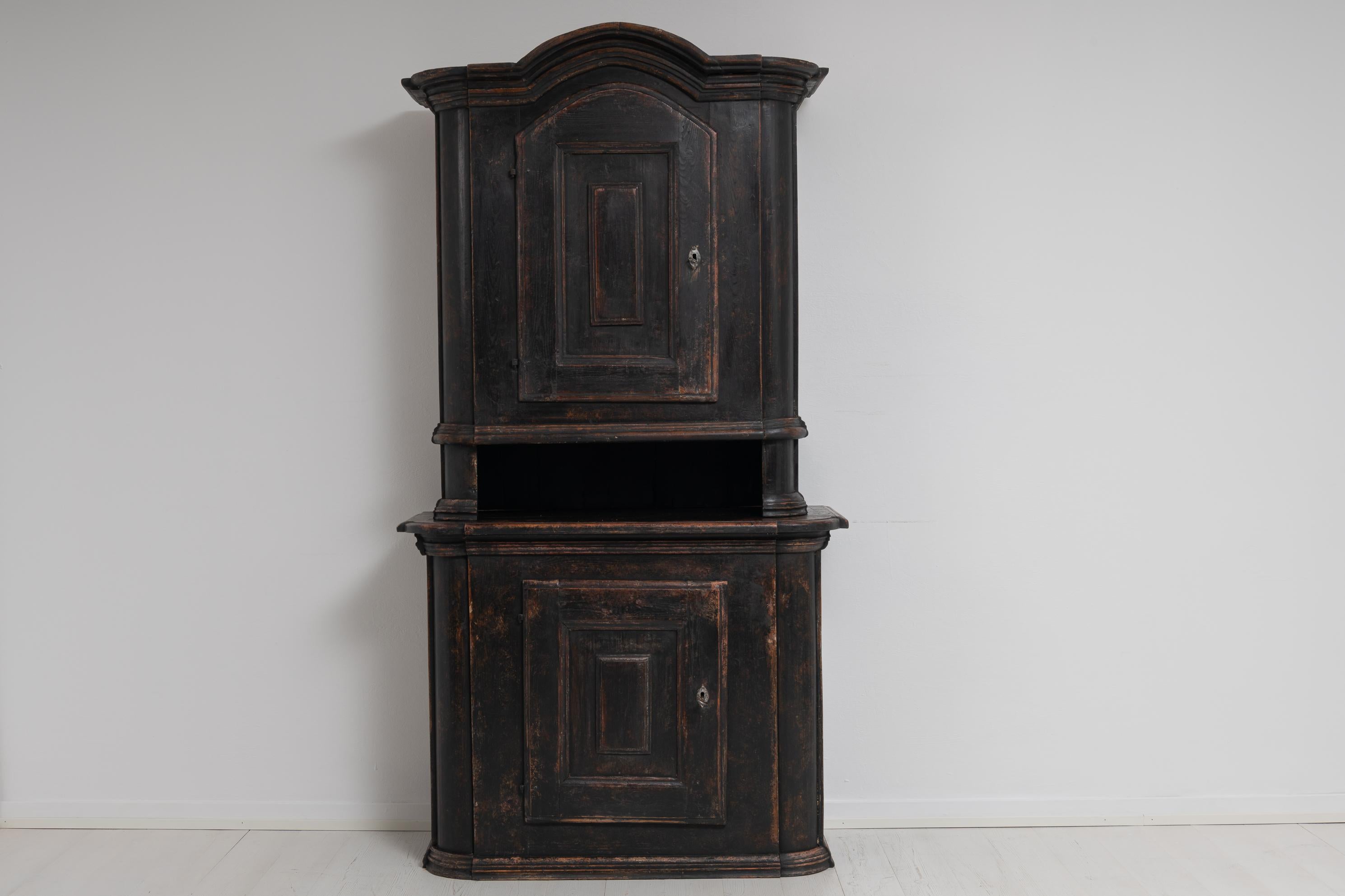 Country house cabinet with distressed black paint from the transitional period between Baroque and Rococo. The cabinet is from Northern Sweden and made during the later part of the 1700s. The cabinet is in 2 parts and made in painted pine. Later