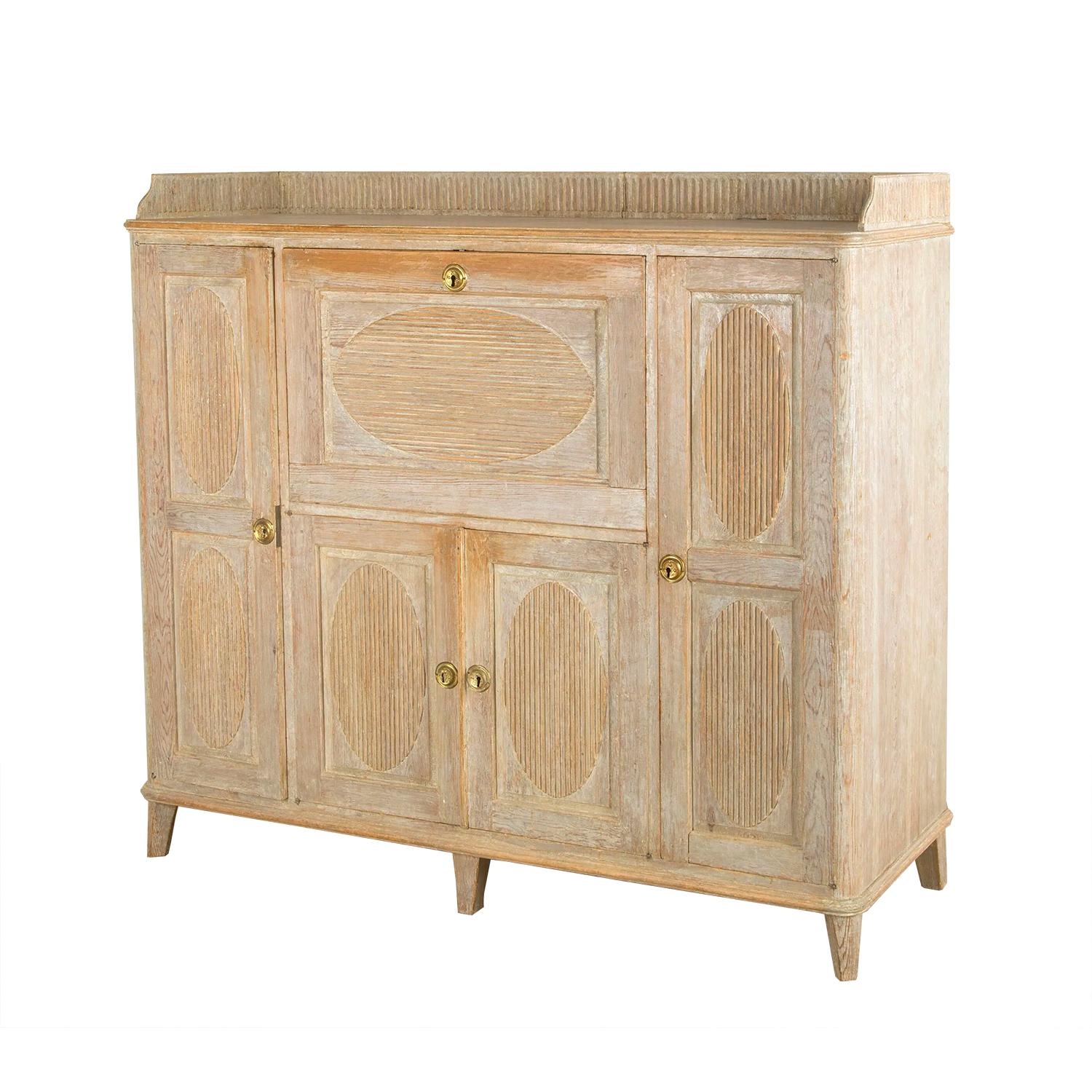 Swedish buffet from Skelleftea with a carved decorated gallery. Featuring a drop front door which opens to a useful desk, with two further long doors opening to storage space. A further two doors open to yet more shelving. 
This is a useful storage
