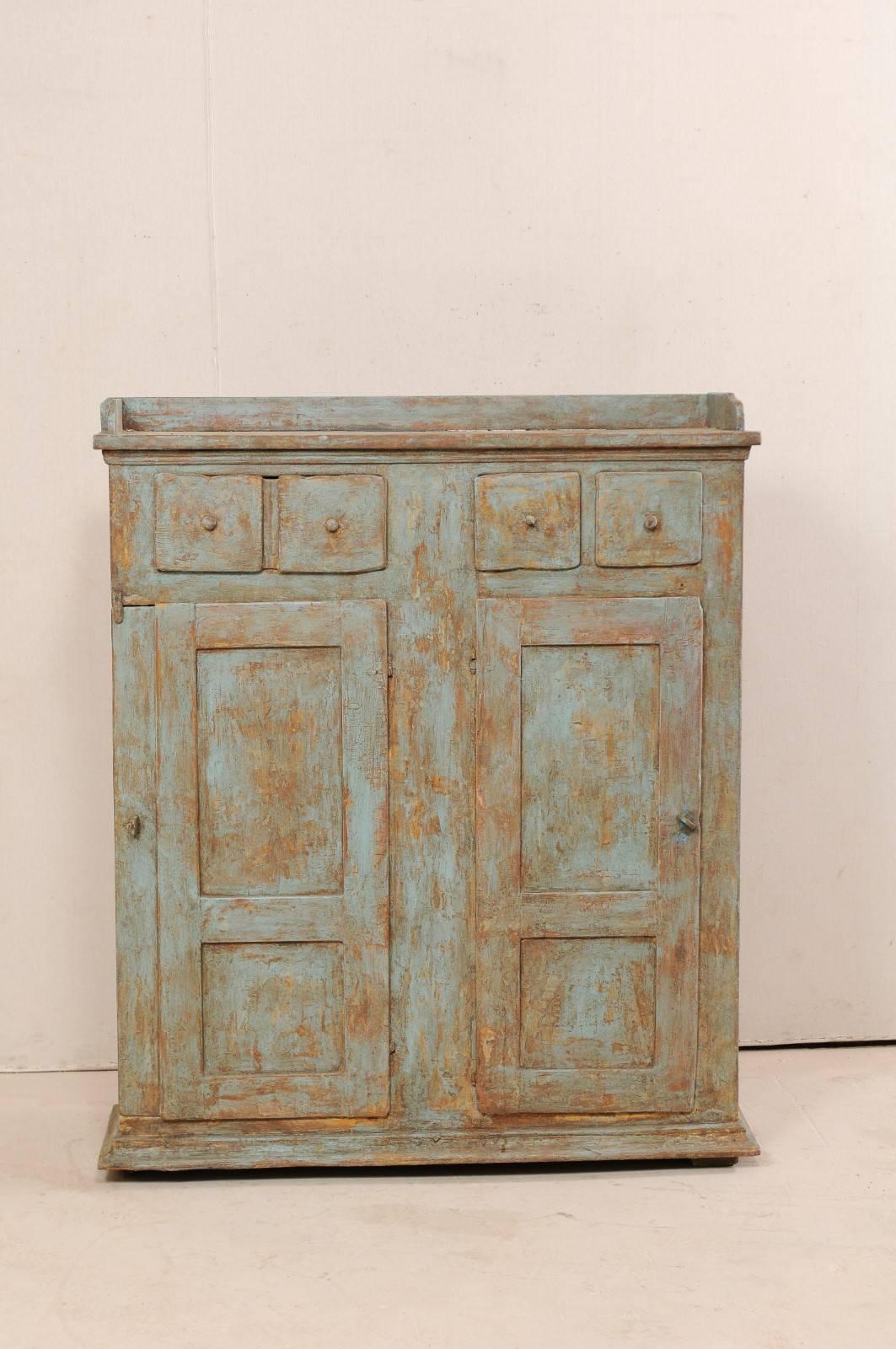 An 18th century Swedish painted wood cabinet. This antique mid-sized cabinet from Sweden features three drawers over two-panelled doors with interior shelves within. The upper left drawer is a half sized drawer, though it's appearance matches that