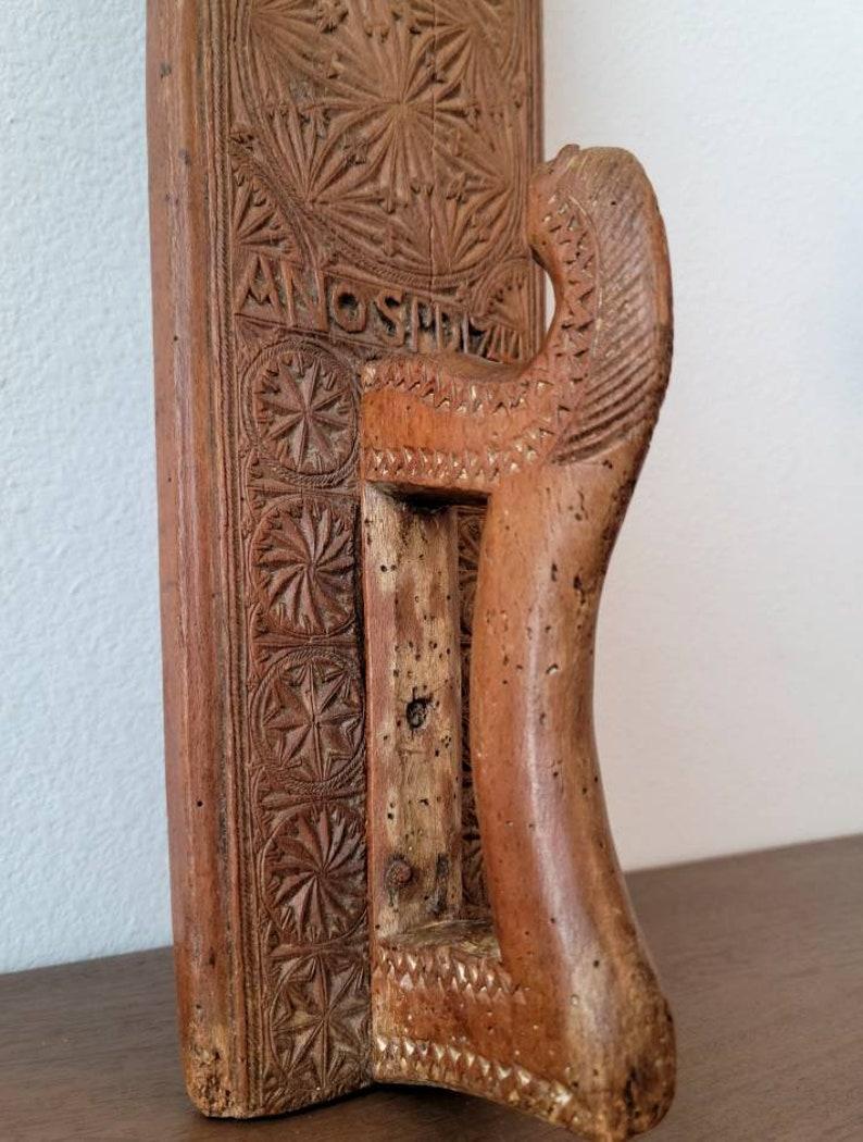 A long hand carved wooden mangle board (clothing and bedding press) with beautiful patina.

Handmade in Sweden, circa 1744, this Scandinavian antique with sculptural stylized horse handle, accented with finely incised detailing, flanked by five