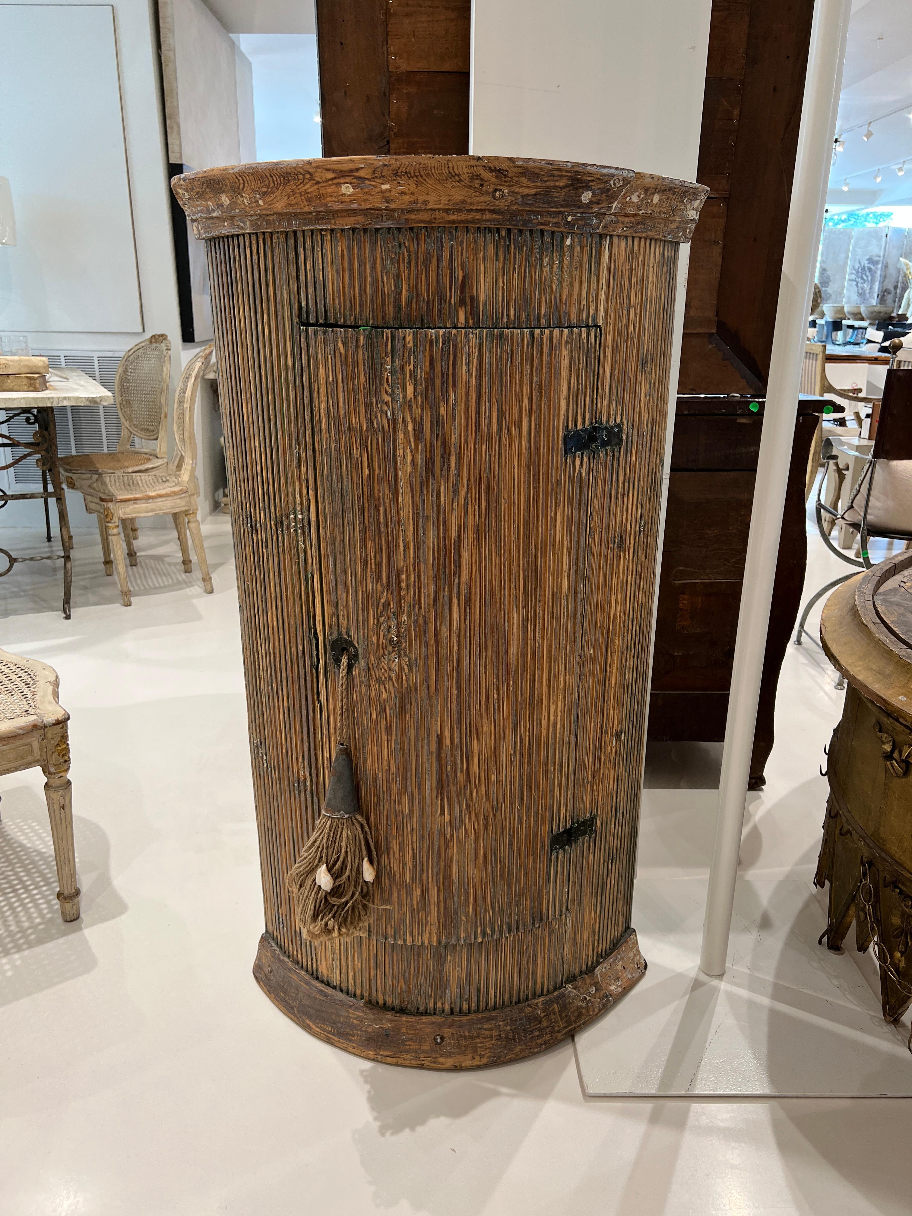 This Swedish Corner Cabinet has a scraped finish exposing shades of ochre, green and natural wood.  The interior is painted olive green.  There is beautiful fluting all around and a full length door with rustic hinges.  The height of the cabinet