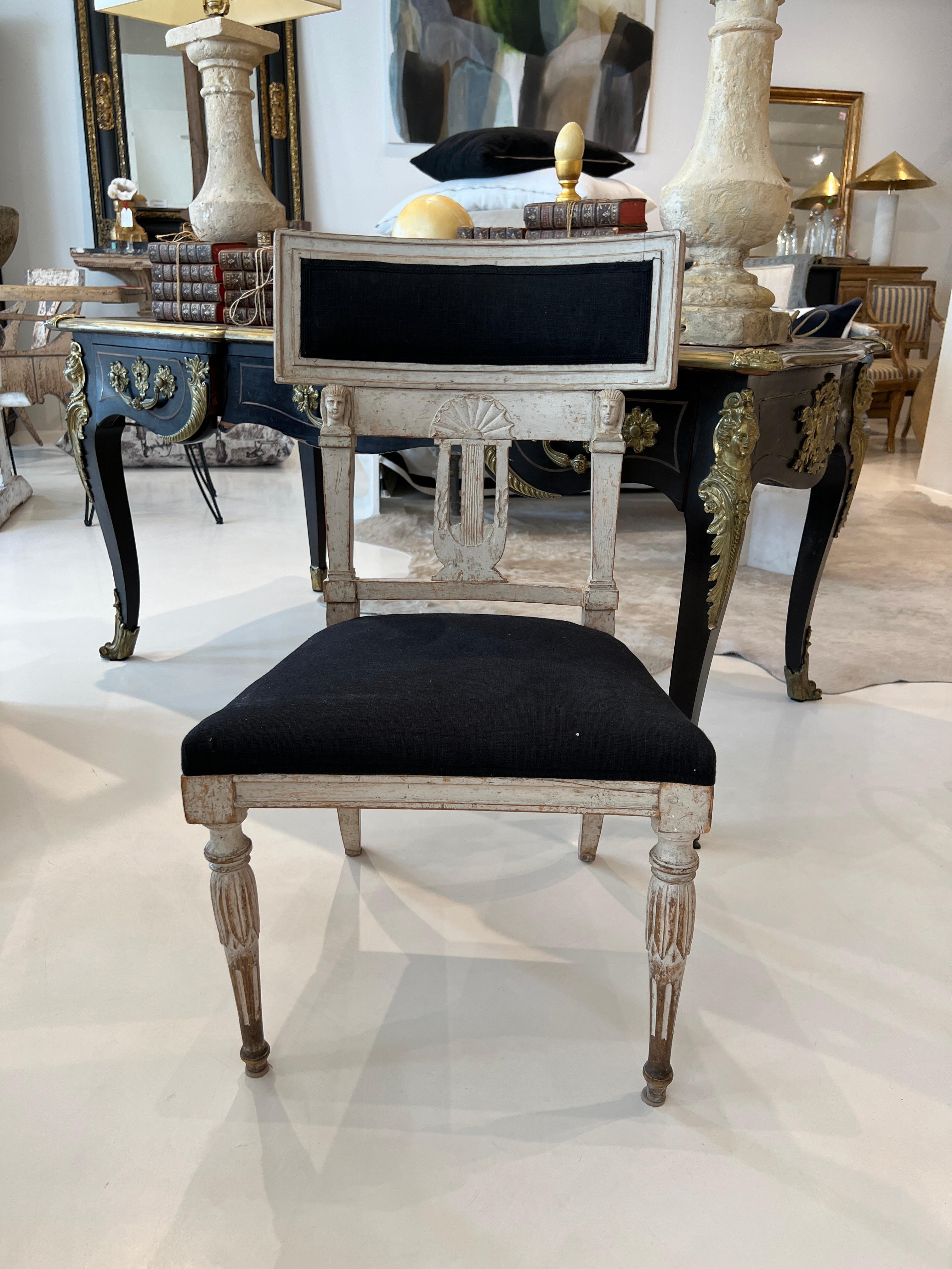 Beautiful Gustavian chair with a surprise.  Two Egyptian faces carved into the back rest.  Soft grey painted wood is set off by black upholstery.