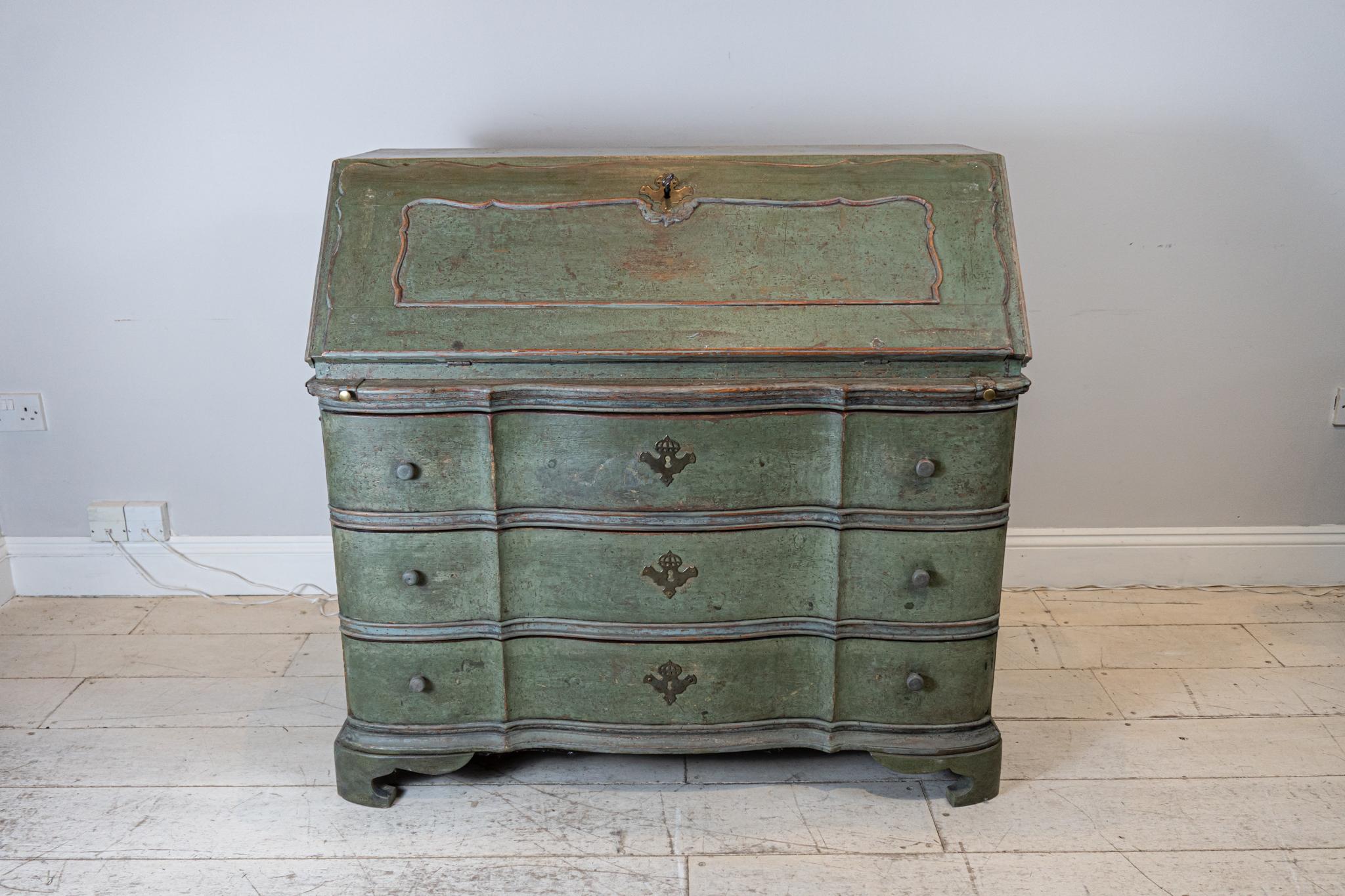 Late Circa 18th century Swedish fall front bureau. The interior comprises of small drawers and compartments over three long deep drawers. The bureau comes in one piece and features decorative iron carrying handles at the sides, and a key.
The paint