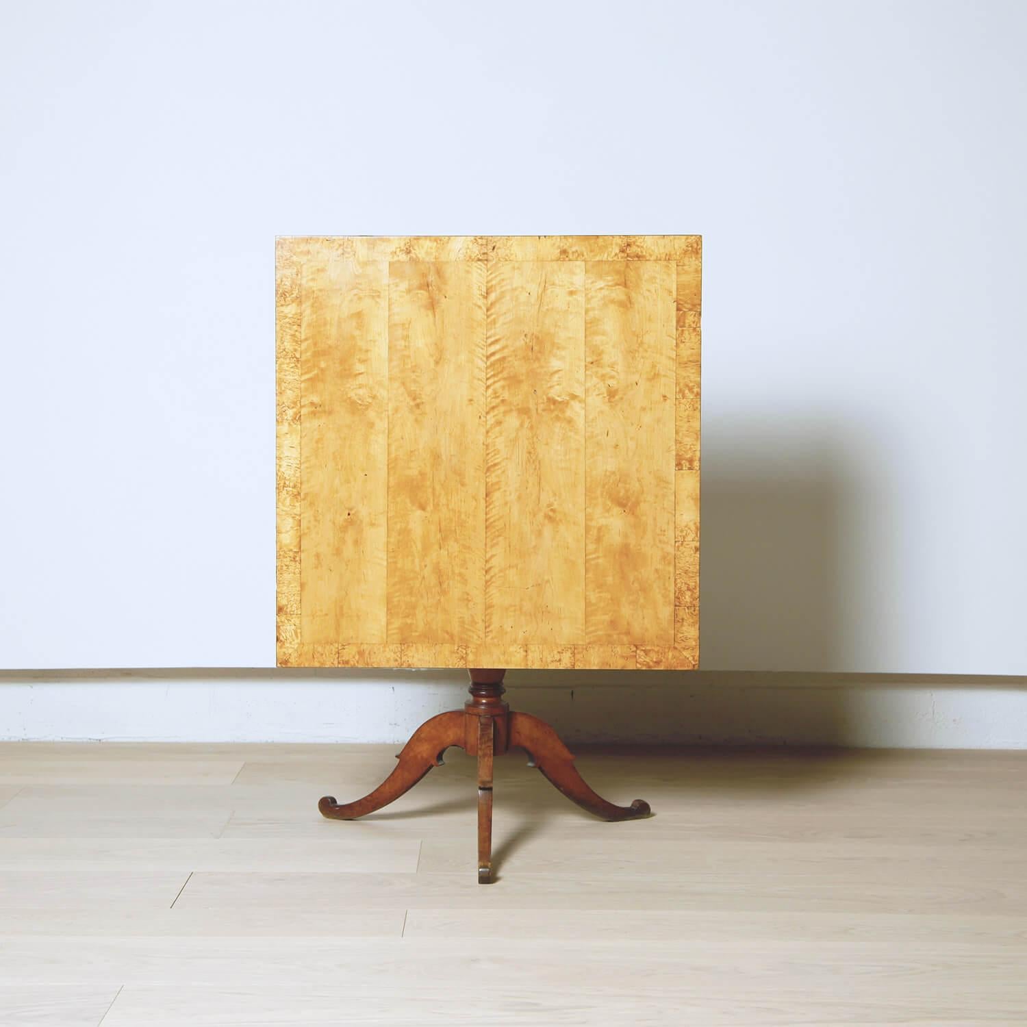 Some furniture reminds us that wood is created by sunlight. This Gustavian flame birch table, for example. The panels of bookmatched veneer on the square top glow. The columnar stem is supported by a delicately carved tripod base.
