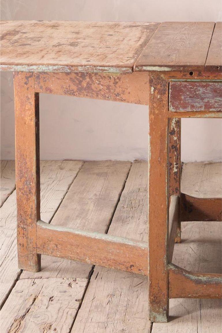 This is a beautifully rustic folk art Swedish gate leg dining table in original paint from over the years. Great patina and overall condition is very good. The sides fold down smoothly and when erect stand sturdily. Great size overall making it