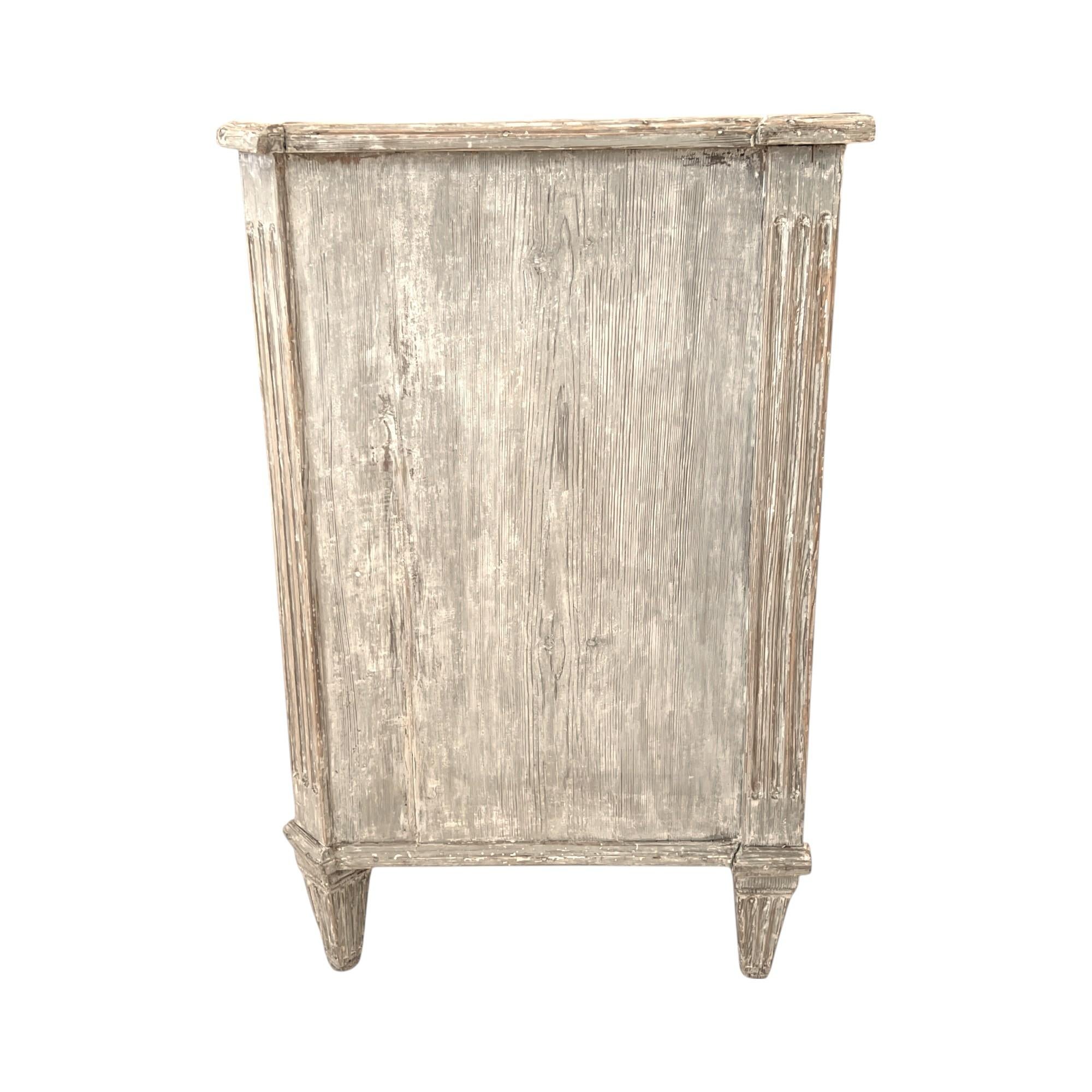 Une charmante petite commode gustavienne peinte dans des tons doux et feutrés, aux lignes épurées et aux détails néoclassiques subtils, parfaite pour ajouter une élégance suédoise discrète et des rangements pratiques à n'importe quelle pièce.
