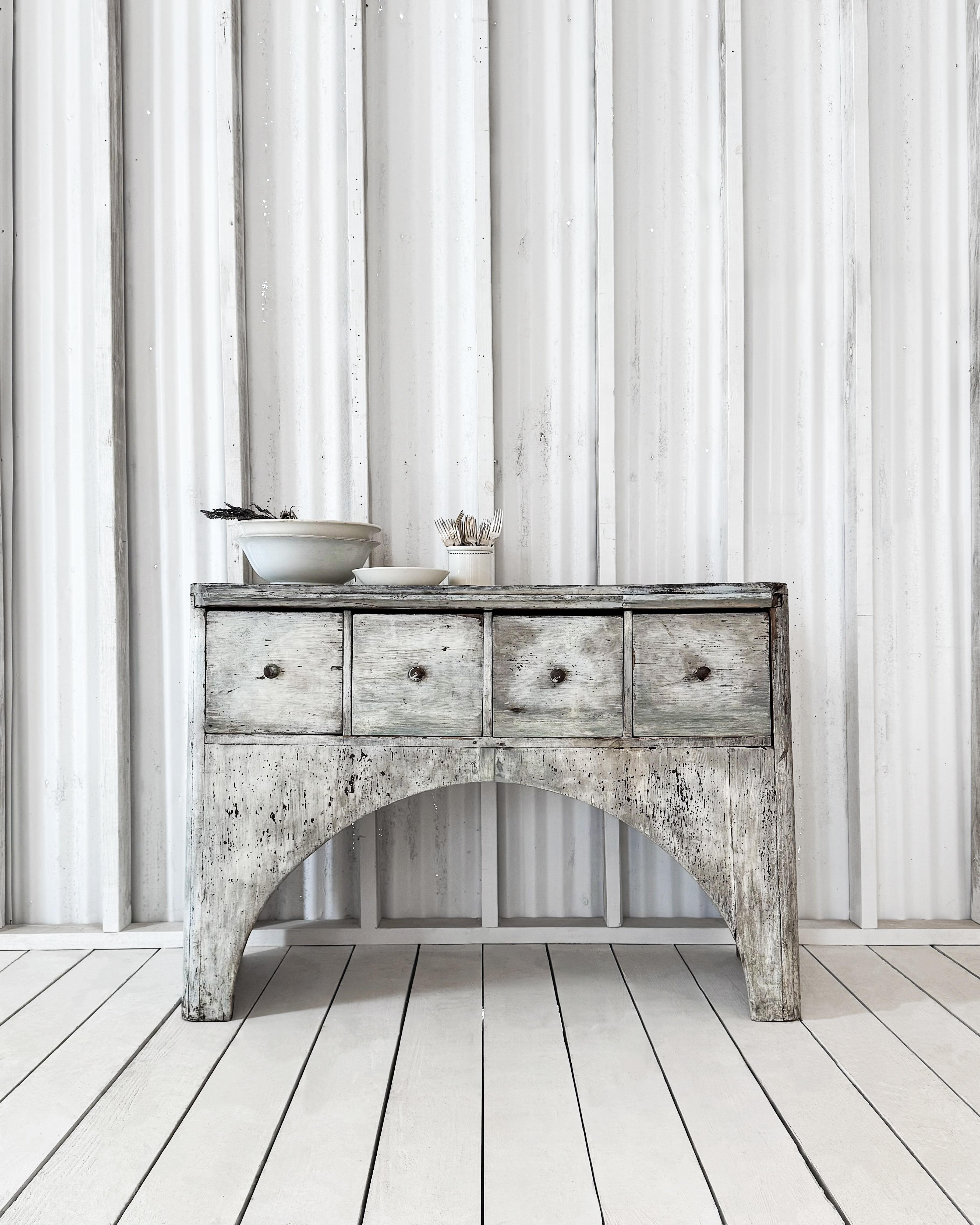 This Gustavian-period Swedish console table features a distinctive arched design that reflects the elegant yet understated style of the era. Crafted from solid wood, the table has its original finish, a timeworn white and pale blue paint with a