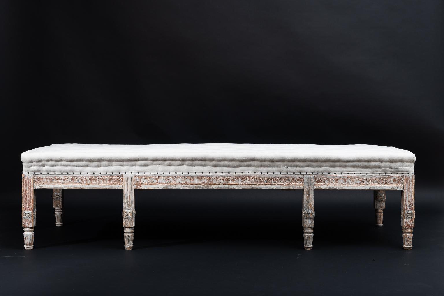 Swedish gustavian bench from the late 1700s. Rustic dry scraped surface with traces of the original paint from the late 1700s. Rich wooden carvings with classic gustavian decor on three sides. The back is not decorated because it is meant to stand