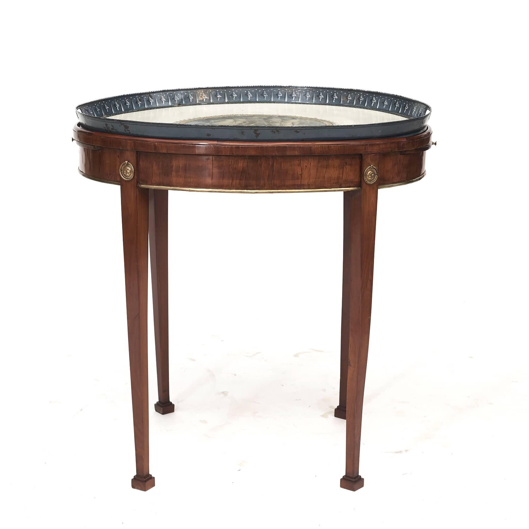Elegant Gustavian metal tray table.
Original oval metal tray decorated with a finely hand painted allegorical scene. Standing rim with pierced handle grips.
Mahogany body, apron complimented with brass trim. Resting on four tapered legs adorned