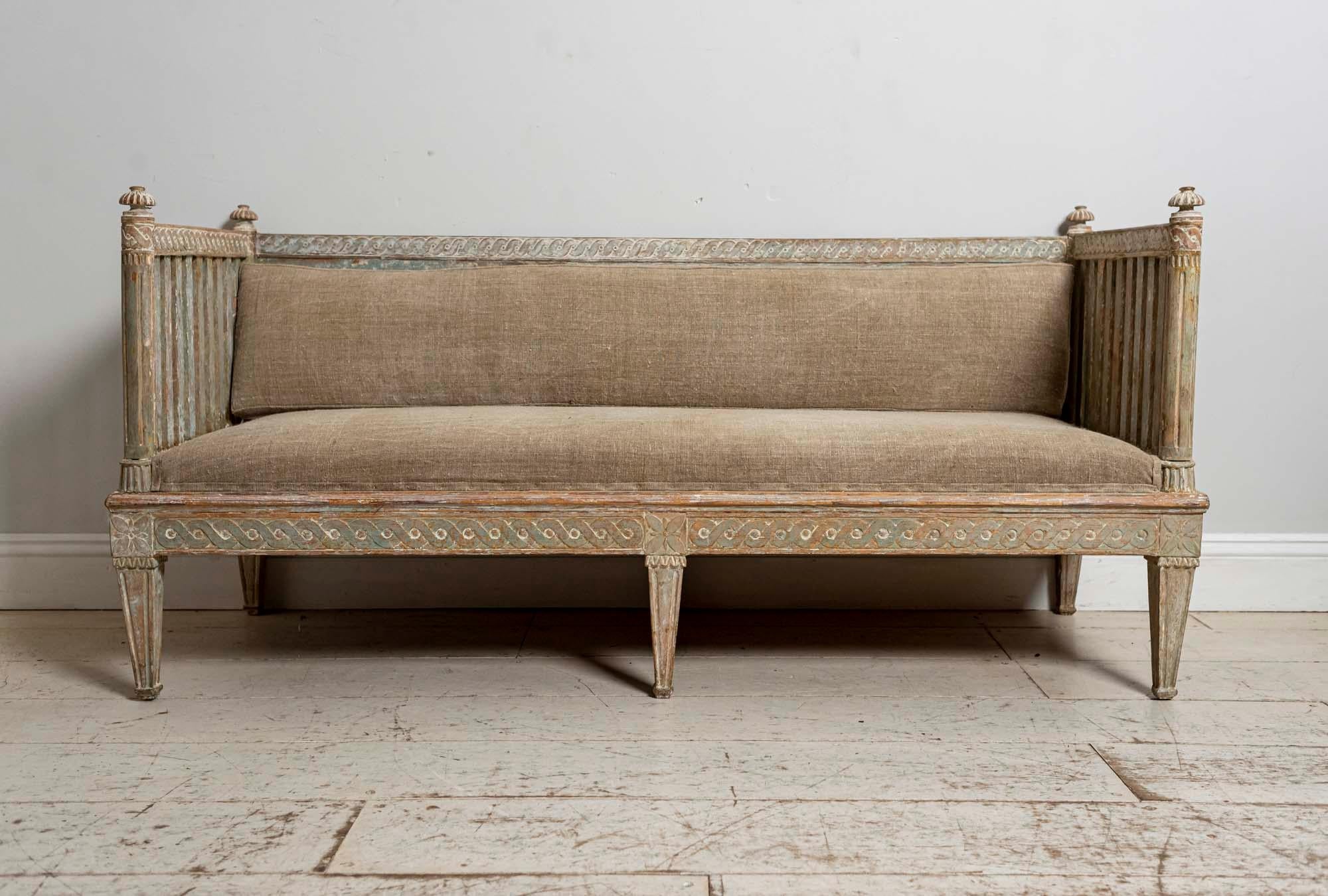 Gorgeous 18th century Gustavian scraped paint Swedish sofa with lovely carving detailing. The sofa has four carved wooden finials on each corner, slatted side supports and a wonderful hand scraped panel back with original blue/green paint with