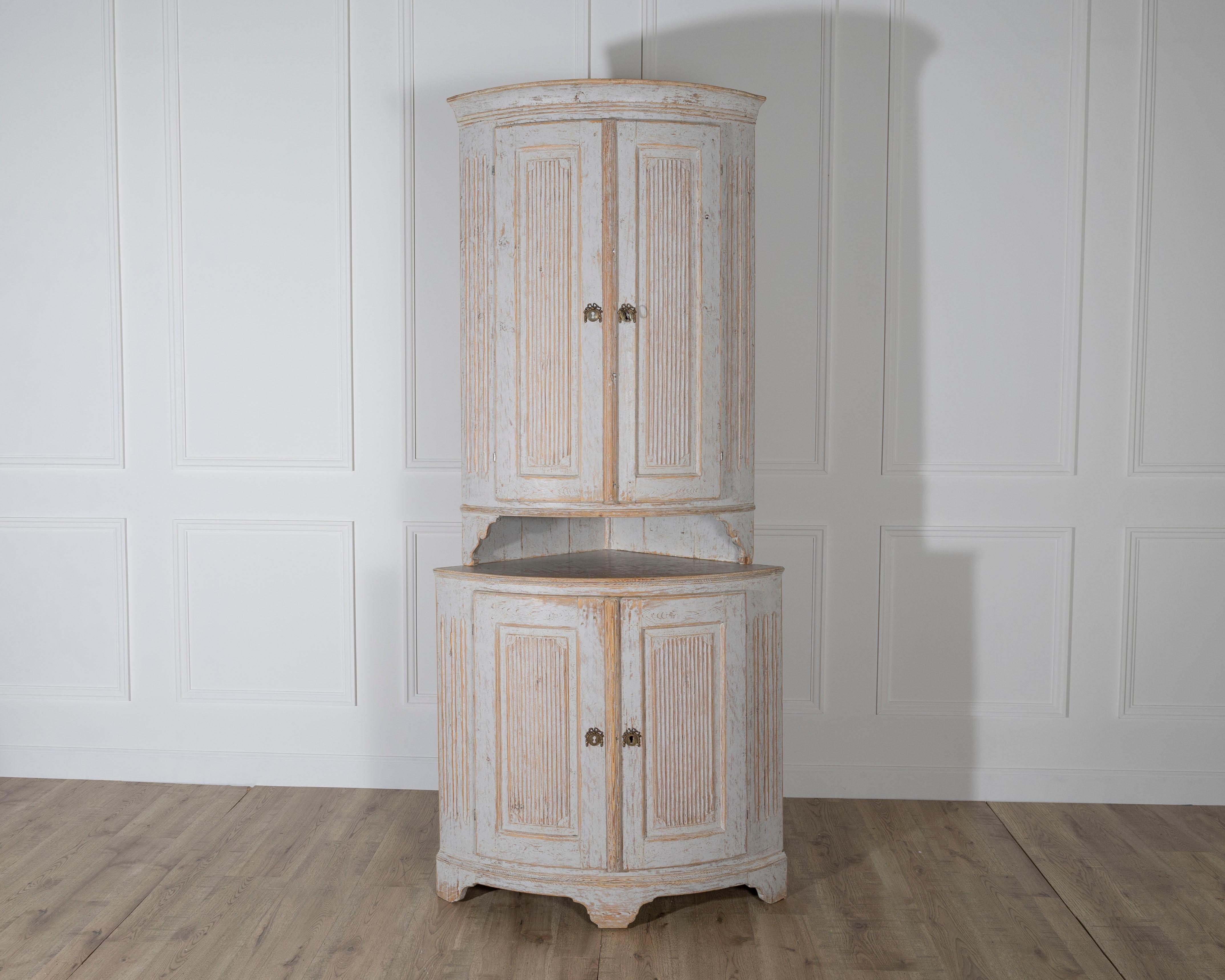 A striking late 18th-century Gustavian period corner cabinet from Sweden, featuring the classic neoclassical elegance of the era. Crafted in two parts, the cabinet showcases paneled doors with reeded details and original brass hardware.

The curved