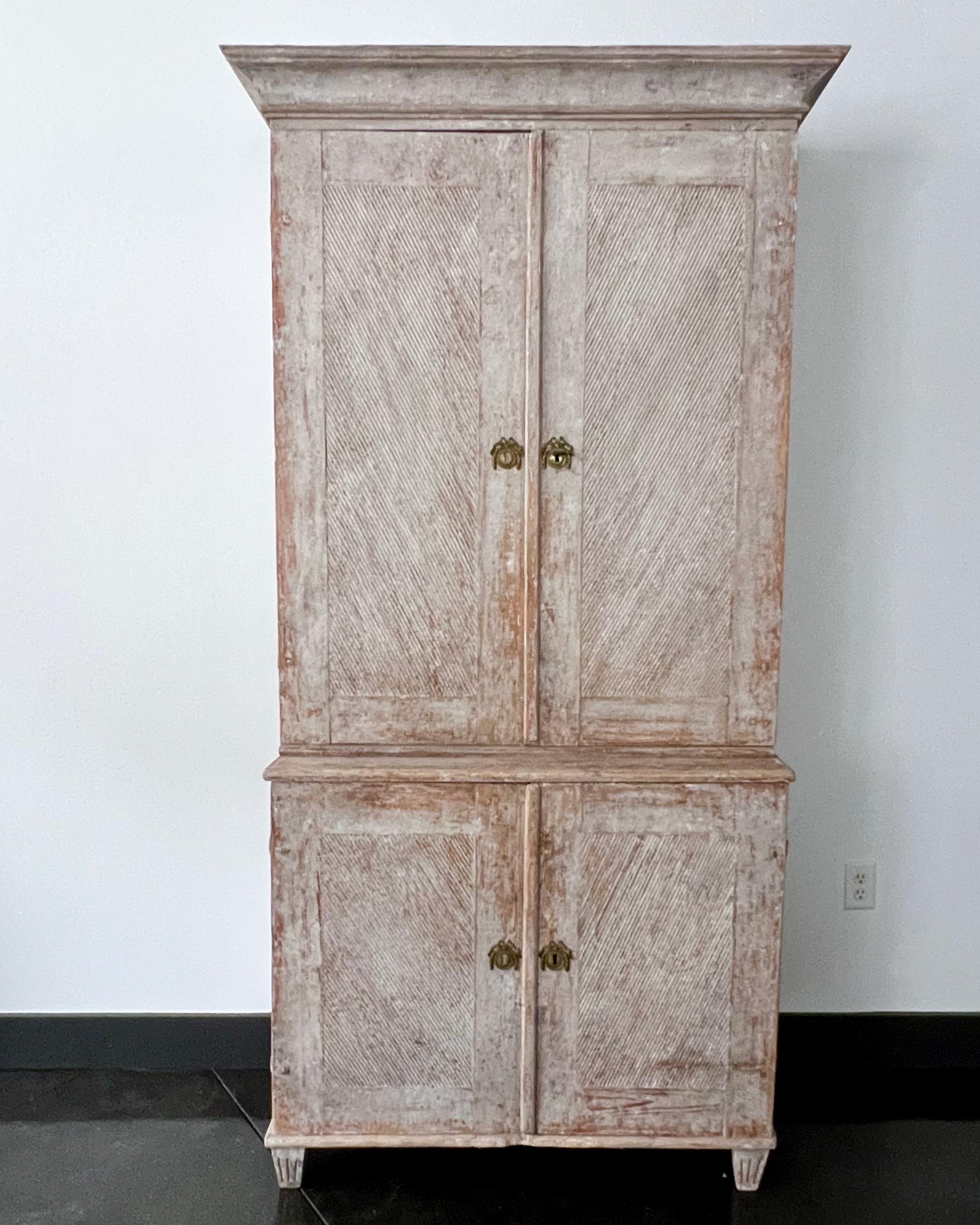 18th century Swedish Gustavian painted cupboard with richly carved unusual angled reeded door panels with beautiful bronze fittings and simple cornice. Lot of storage with inside wider and smaller selves. All in lovely pale gray patina.