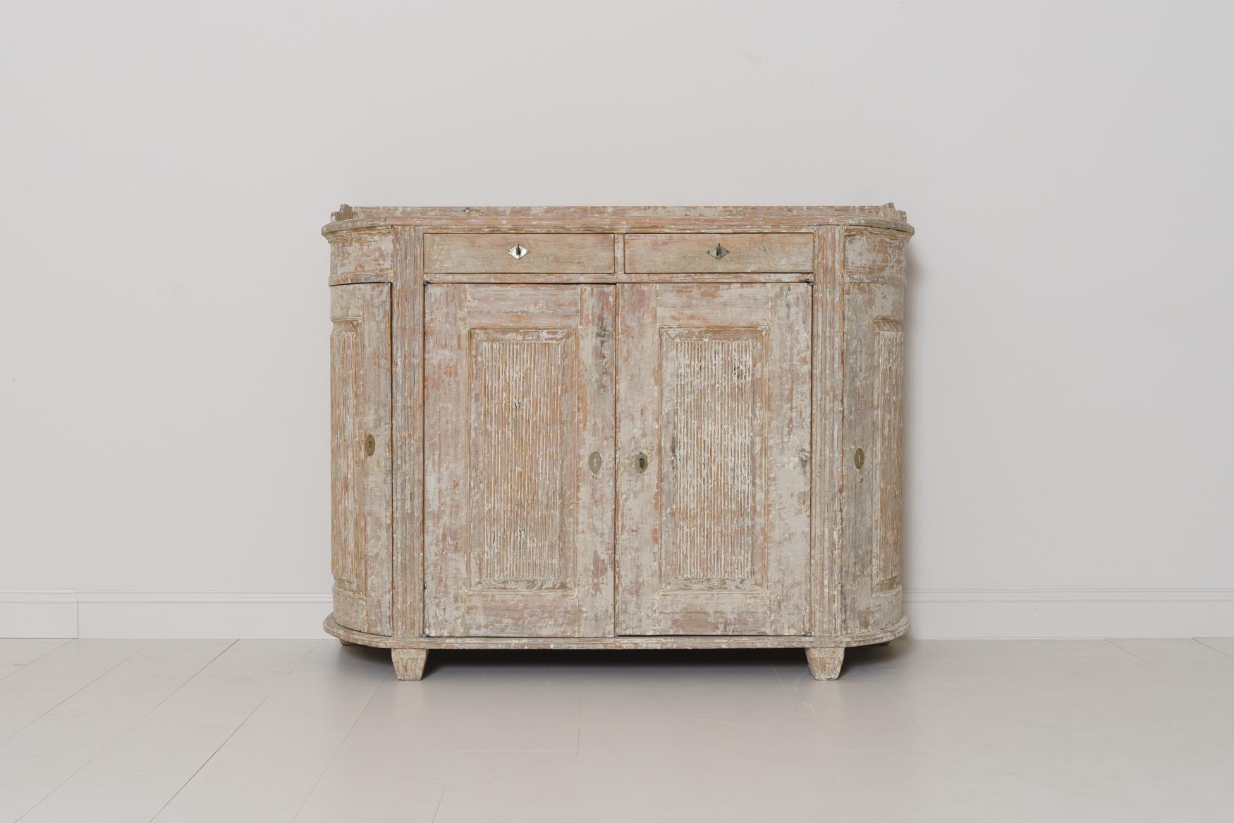 A Swedish demilune sideboard or server in original paint from the Gustavian period.  The patina is a beautiful chalky old ivory-white with natural wood showing through in areas. The buffet has two drawers and three reeded, raised panel doors. The
