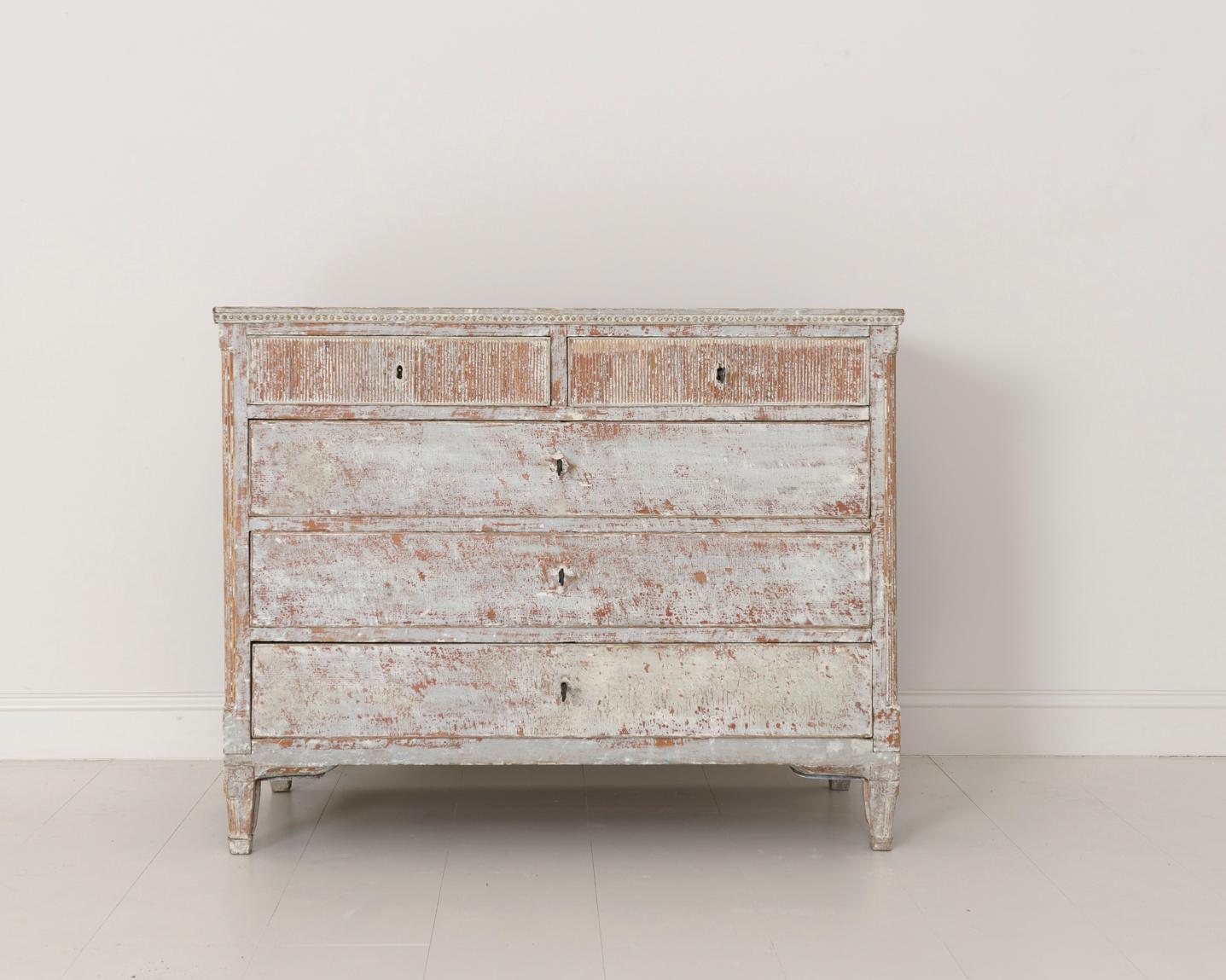 A stunning Swedish commode from the Gustavian period hand-scraped to reveal the original, soft gray paint with traces of the original dark red primer peaking through in areas. The trim around the top is beaded and below there are two smaller reeded