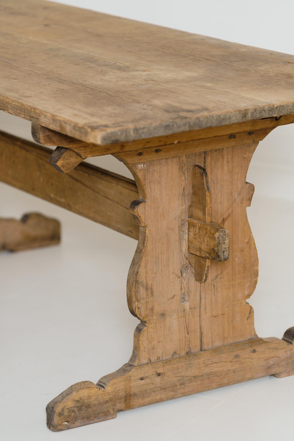 A charming Swedish trestle dining table, circa 1770, with a deep, honey-colored patina. It has a beautiful plank top with central stretcher and shaped sides. This rustic allmoge (countryfolk) table has a time worn, untouched, original patina.  The