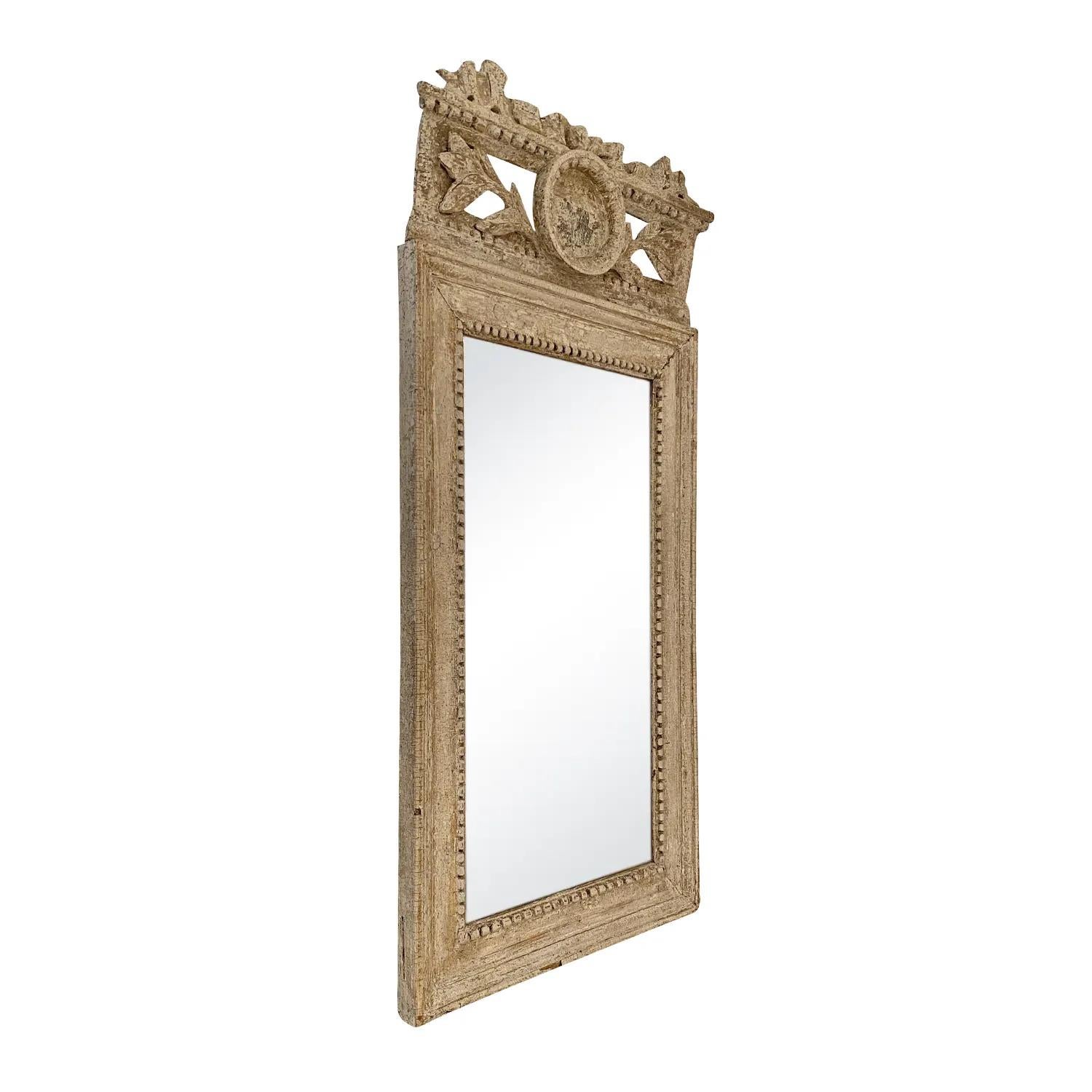 A light-grey, white antique Swedish Gustavian wall mirror made of hand carved pinewood with its original mirrored glass, in good condition. The particularized Scandinavian wall décor piece is enhanced by detailed flower carvings and fittings. Wear