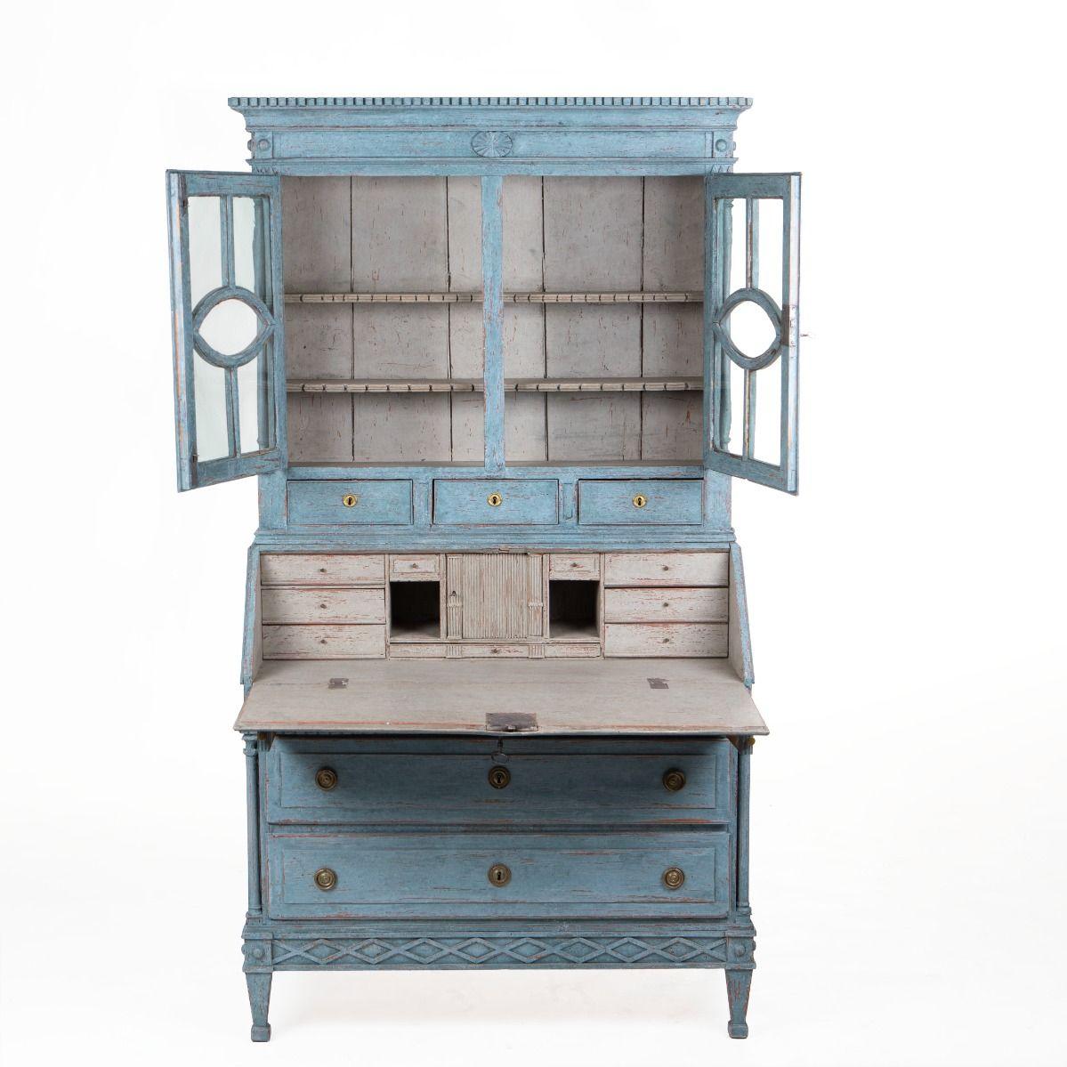Gustavian secretary crafted in pine, finished in a charming blue tone with an elegant patina.

The piece is composed of two sections with refined detailing throughout.
The upper cabinet features a pair of glazed doors beneath a cornice with dentil